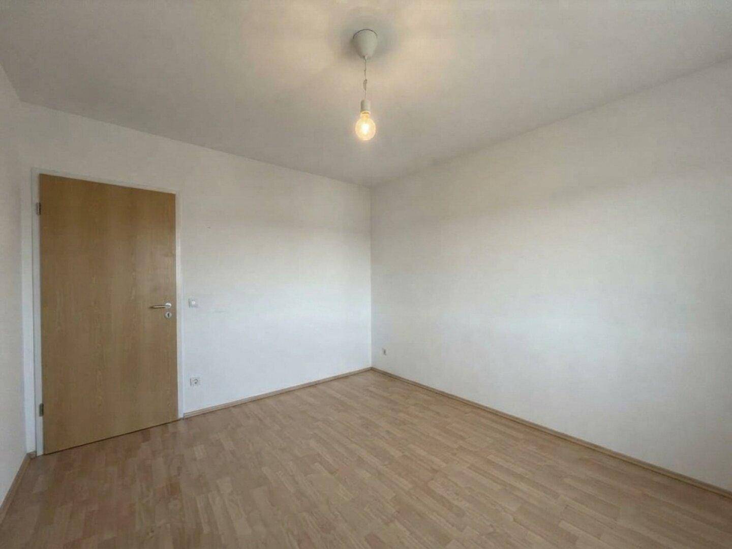 Geräumiges Schlafzimmer mit Parkettboden und einer Holztür.
