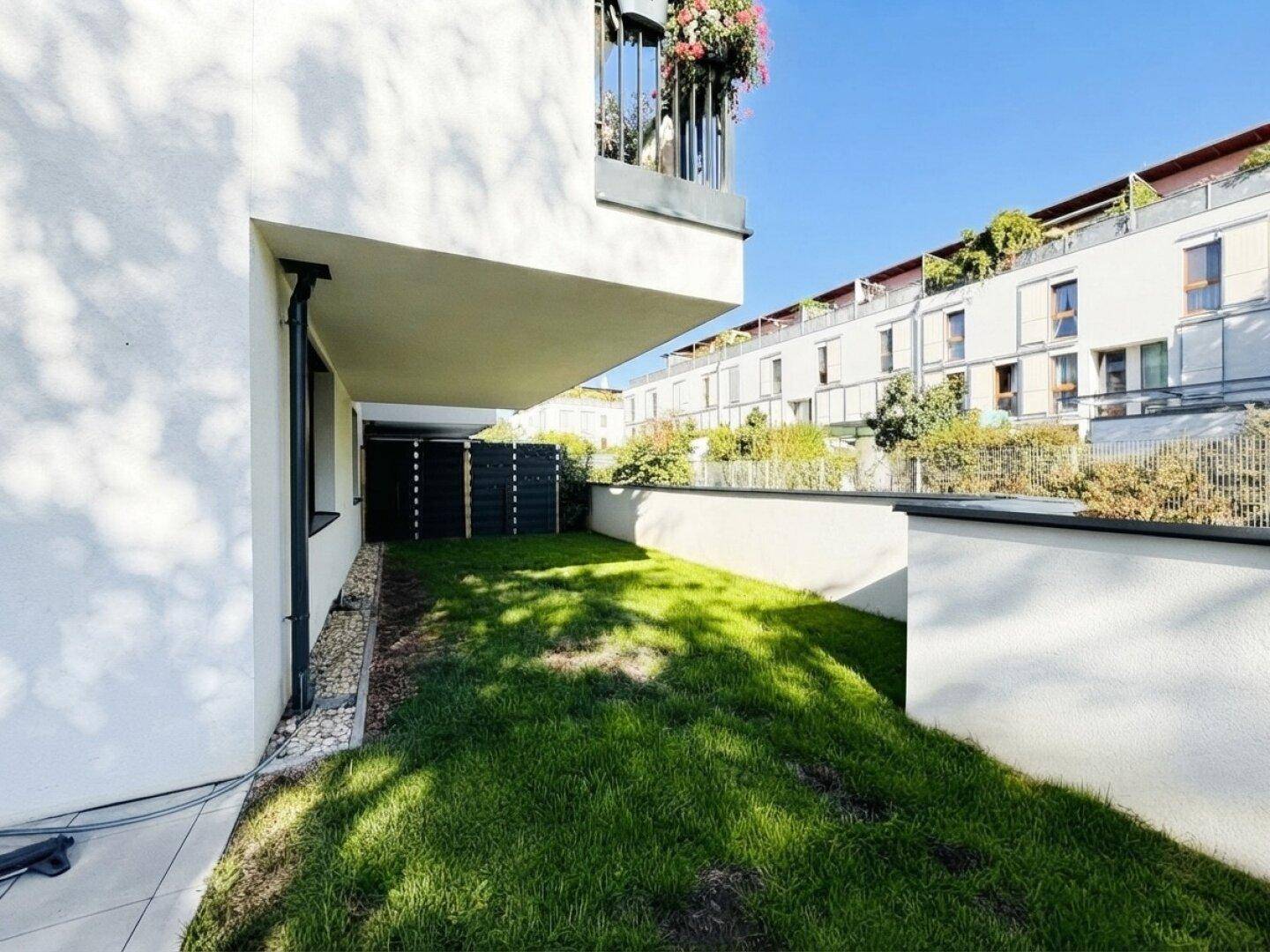 Seitlicher Gartenbereich mit Rasenfläche und Blick auf die umliegenden Gebäude.