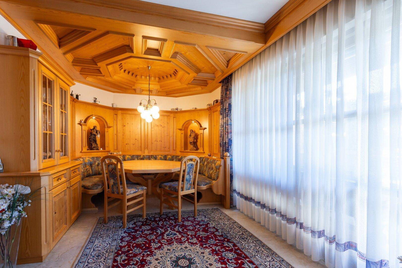 Gemütlicher Essbereich im alpenländischen Stil mit Holztäfelung, Eckbank und geschnitzten Details.