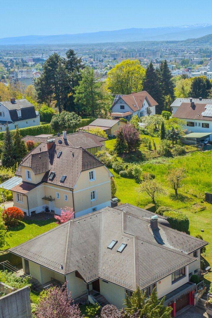 Panoramablick auf eine Wohngegend mit Häusern, Gärten und weitem Horizont.