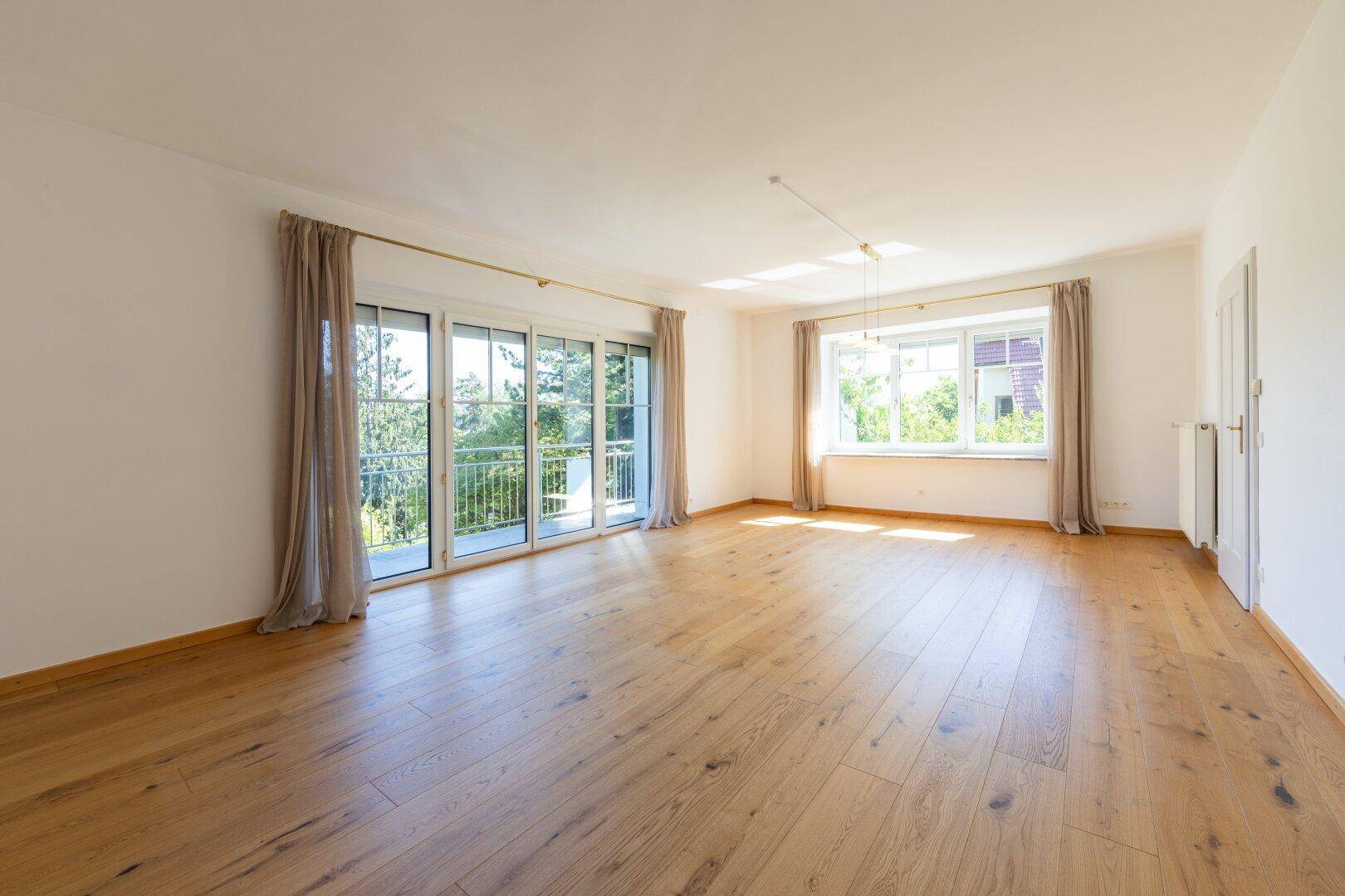 Großes, helles Wohnzimmer mit Holzboden, vielen Fenstern und viel natürlichem Licht.