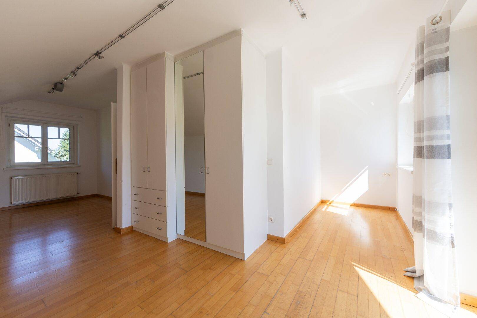 Helles Schlafzimmer mit Holzboden, Einbauschränken und vielseitig nutzbarem Raum.