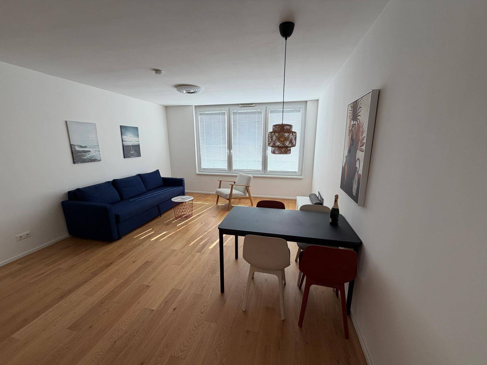 Gemütlicher Wohn- und Essbereich mit Holzboden, blauem Sofa und modernem Esstisch.