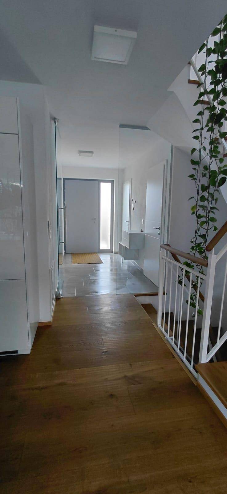 Heller Eingangsbereich mit Holztreppe, Garderobe und Blick zum Hauseingang.