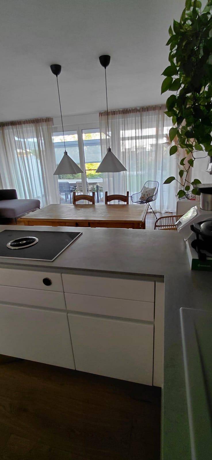 Moderne Küche mit Induktionskochfeld und Essbereich im Hintergrund, hell und offen gestaltet.