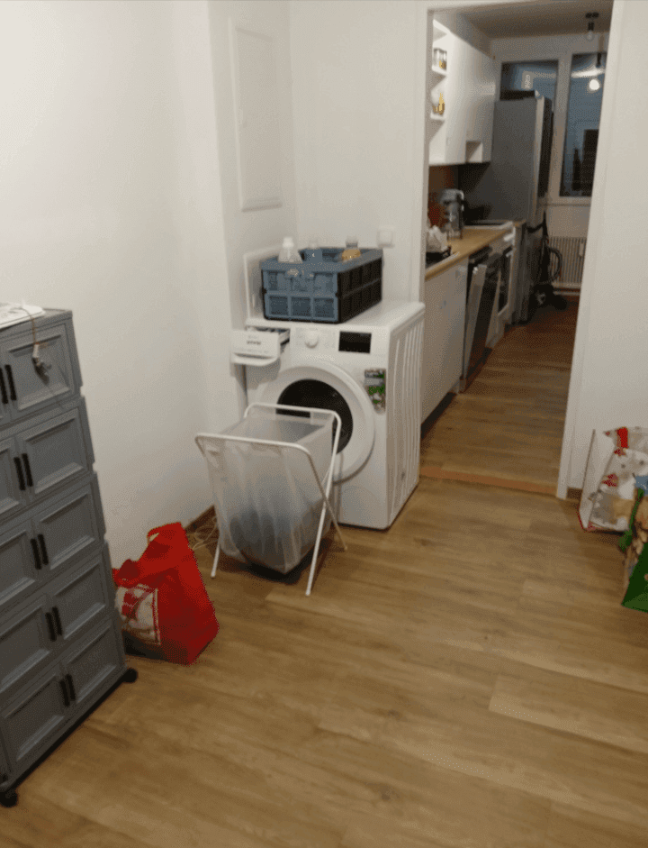 Flur mit Waschmaschine und Wäschekorb, angrenzend an die Küche.