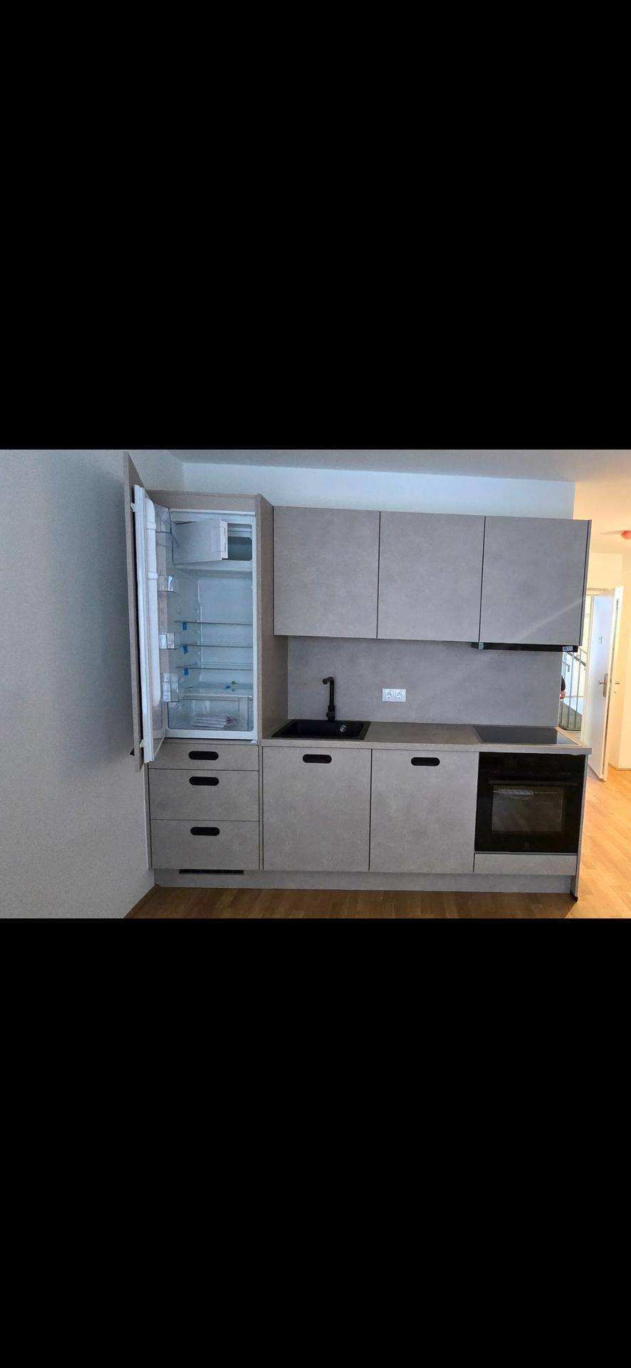 Moderne Einbauküche in Grau mit integriertem Kühlschrank und Backofen.