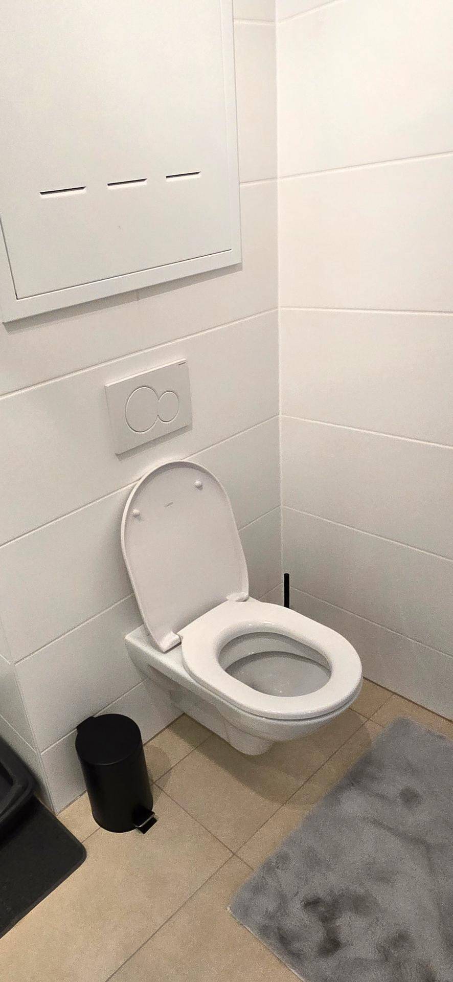 Wandhängendes WC in einem hell gefliesten Raum, möglicherweise ein Gäste-WC.