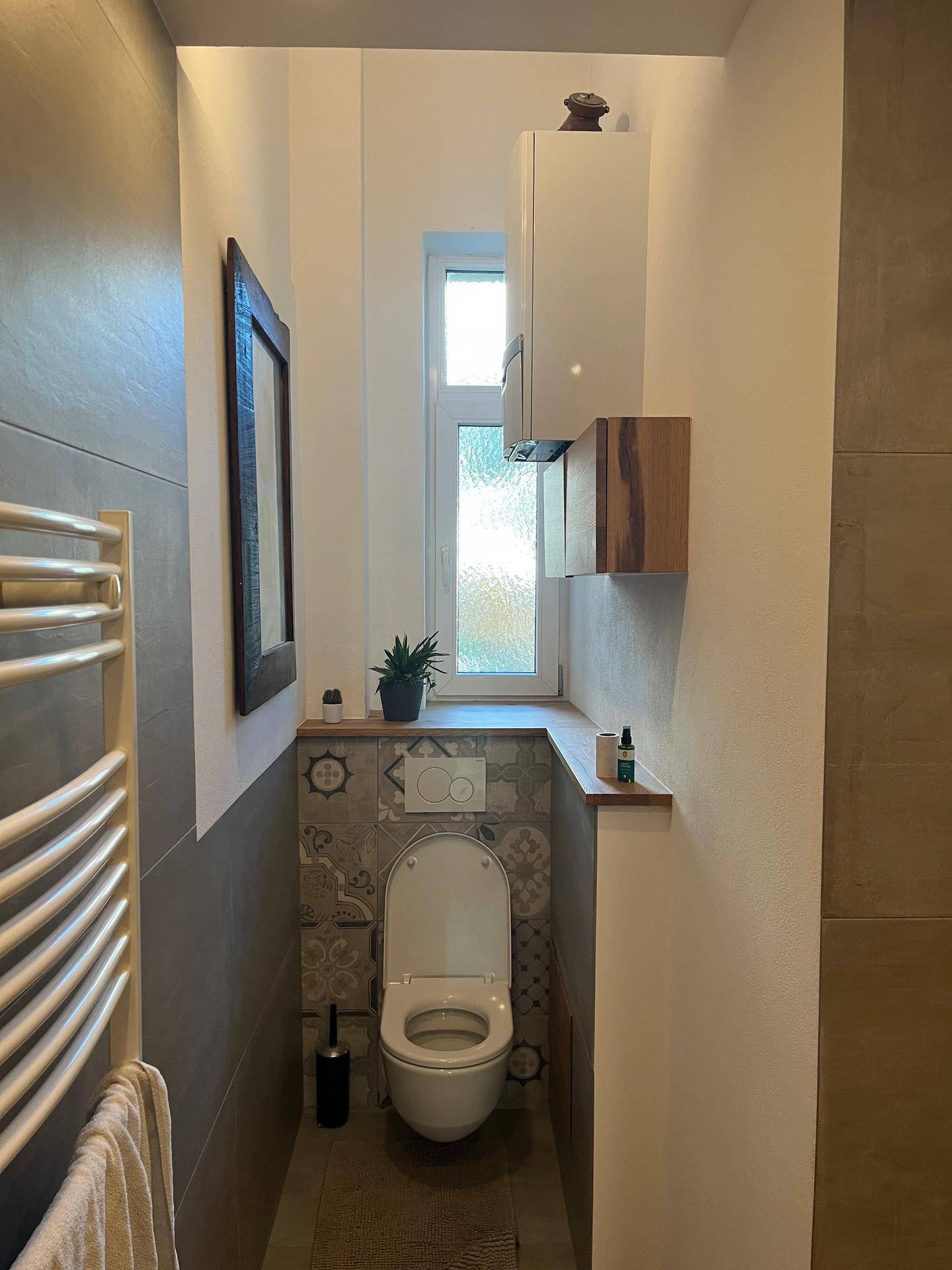 Modernes WC mit Wand-WC, Fliesen und einem Fenster für Tageslicht.