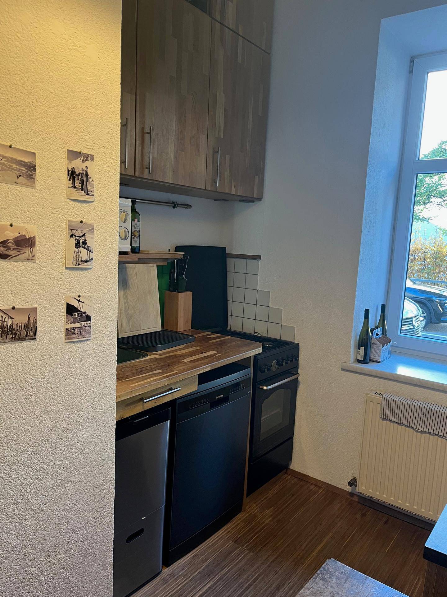 Küchenzeile mit Holz-Arbeitsplatte, Spülmaschine und Herd, neben einem Fenster.