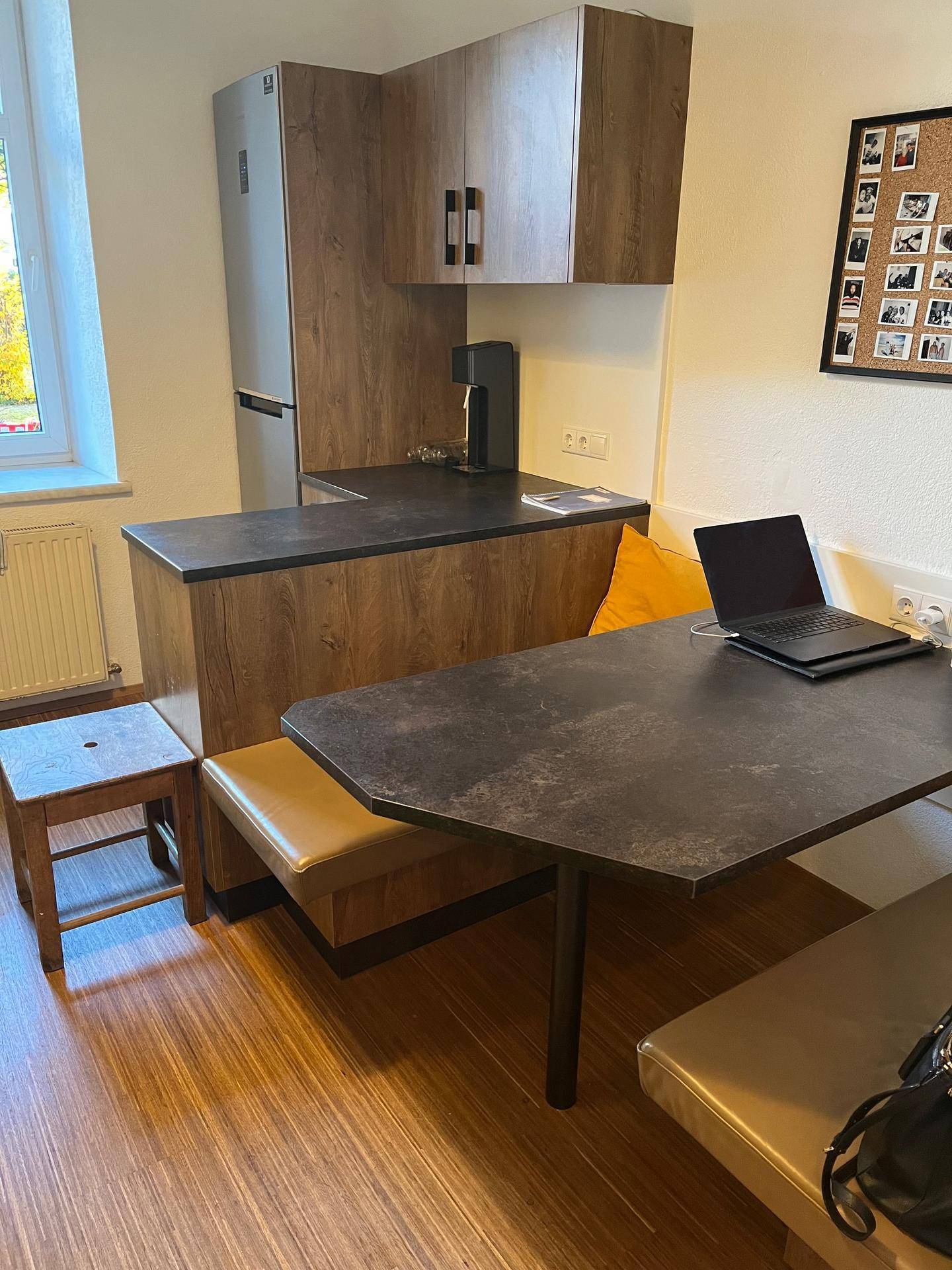 Kompakte Küche mit Holzelementen, integriertem Essbereich und modernen Geräten.