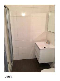 Modernes Badezimmer mit Duschkabine, weißem Waschtisch und hellen Wandfliesen.