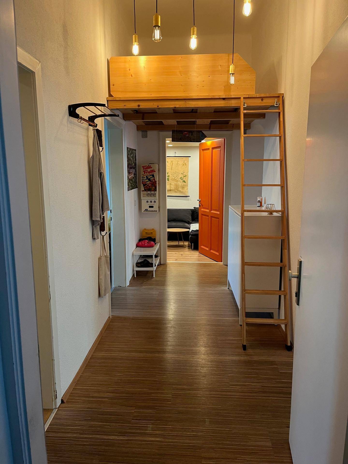 Heller Flur mit Holzfußboden und einer Holzleiter, die zu einem Hochbett führt.