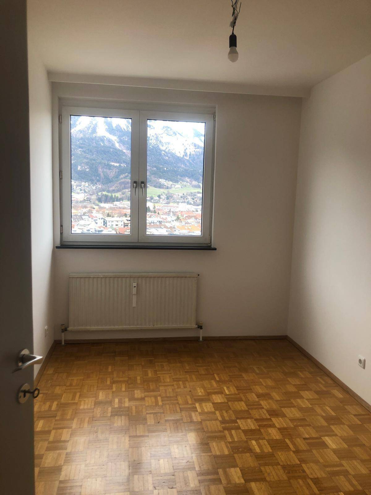 Schlafzimmer mit Parkettboden und einem großen Fenster, das einen weiten Bergblick bietet.