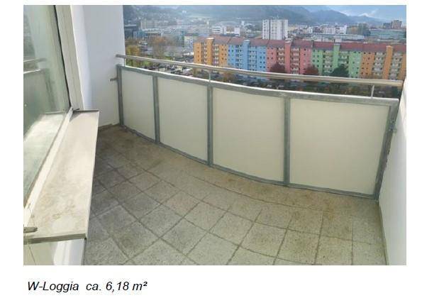 Überdachte Loggia mit Fliesenboden und Blick auf die umliegende Stadtbebauung.