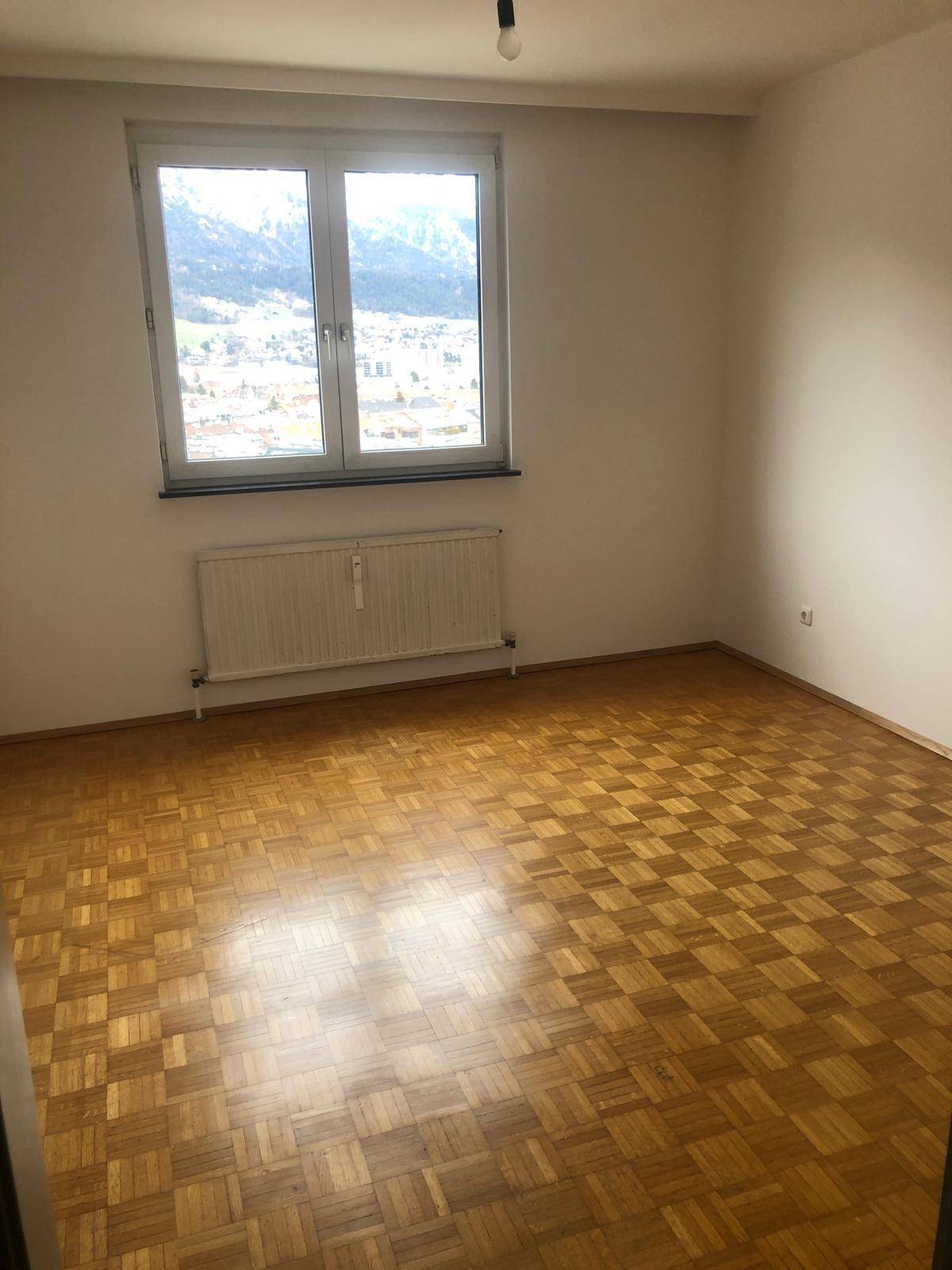 Geräumiges Schlafzimmer mit Parkettboden und Fenster, das einen beeindruckenden Bergblick freigibt.