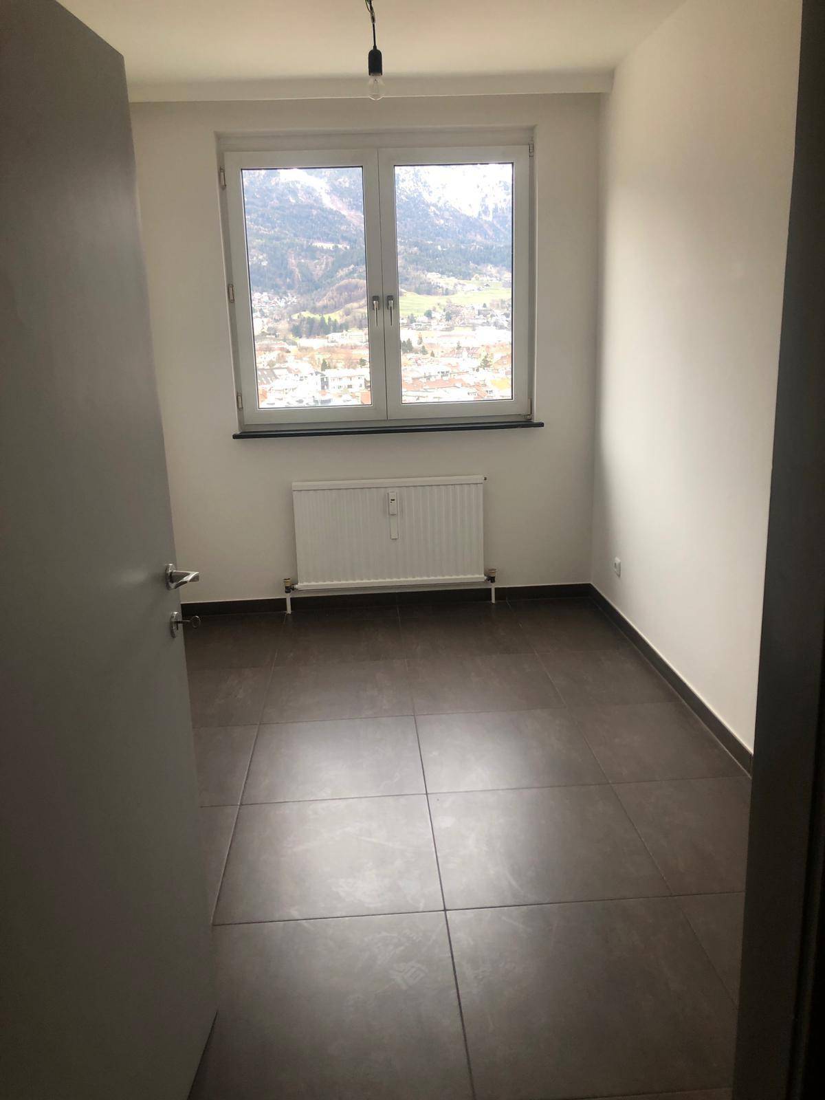 Zimmer mit dunklen Fliesen und Fenster, das einen malerischen Blick auf die Berge bietet.