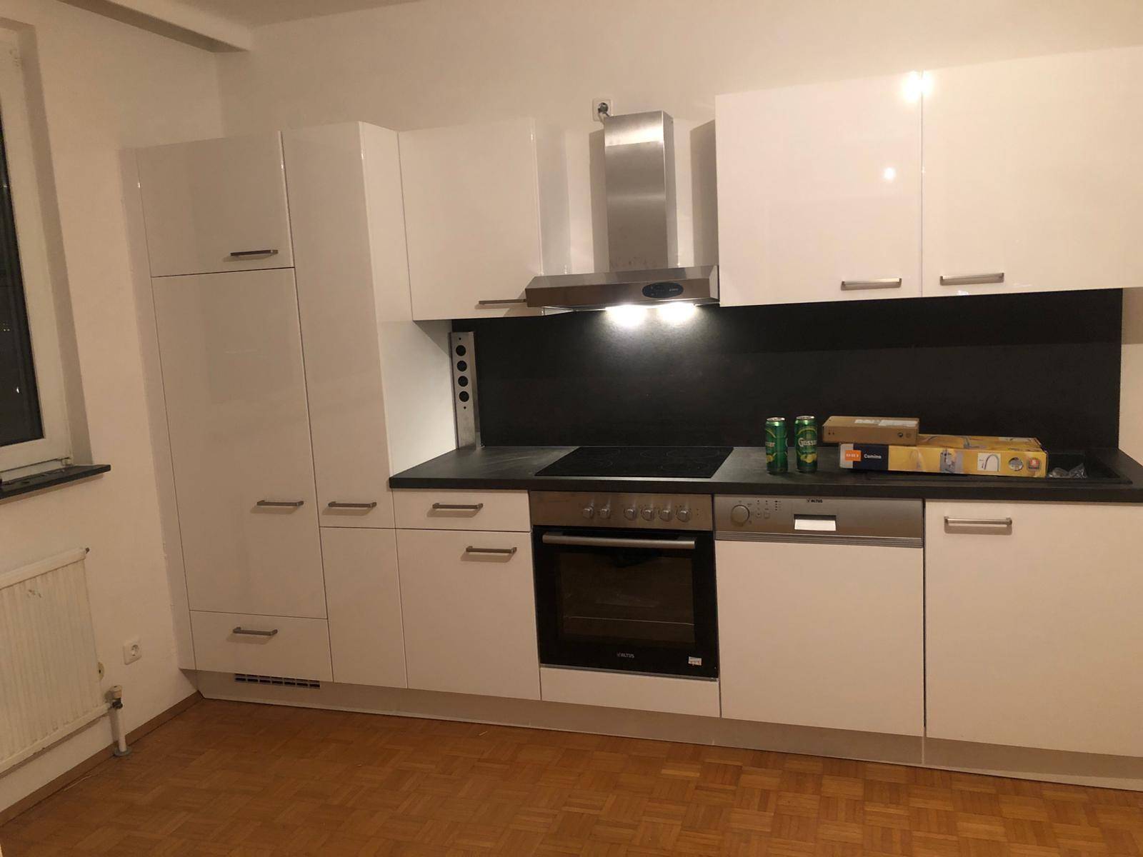Moderne Einbauküche mit weißen Hochglanzfronten, Induktionskochfeld und integrierten Geräten.