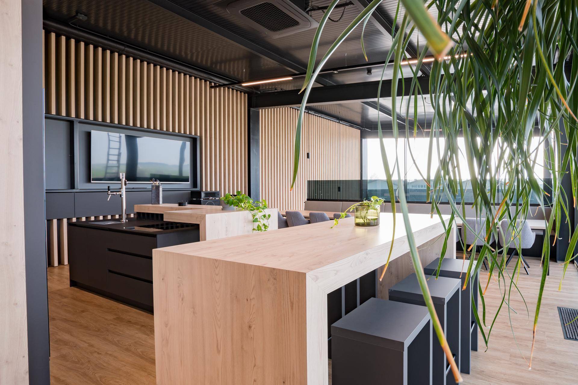 Moderne Küche und Loungebereich mit Holzelementen, Barhockern und Fernseher.