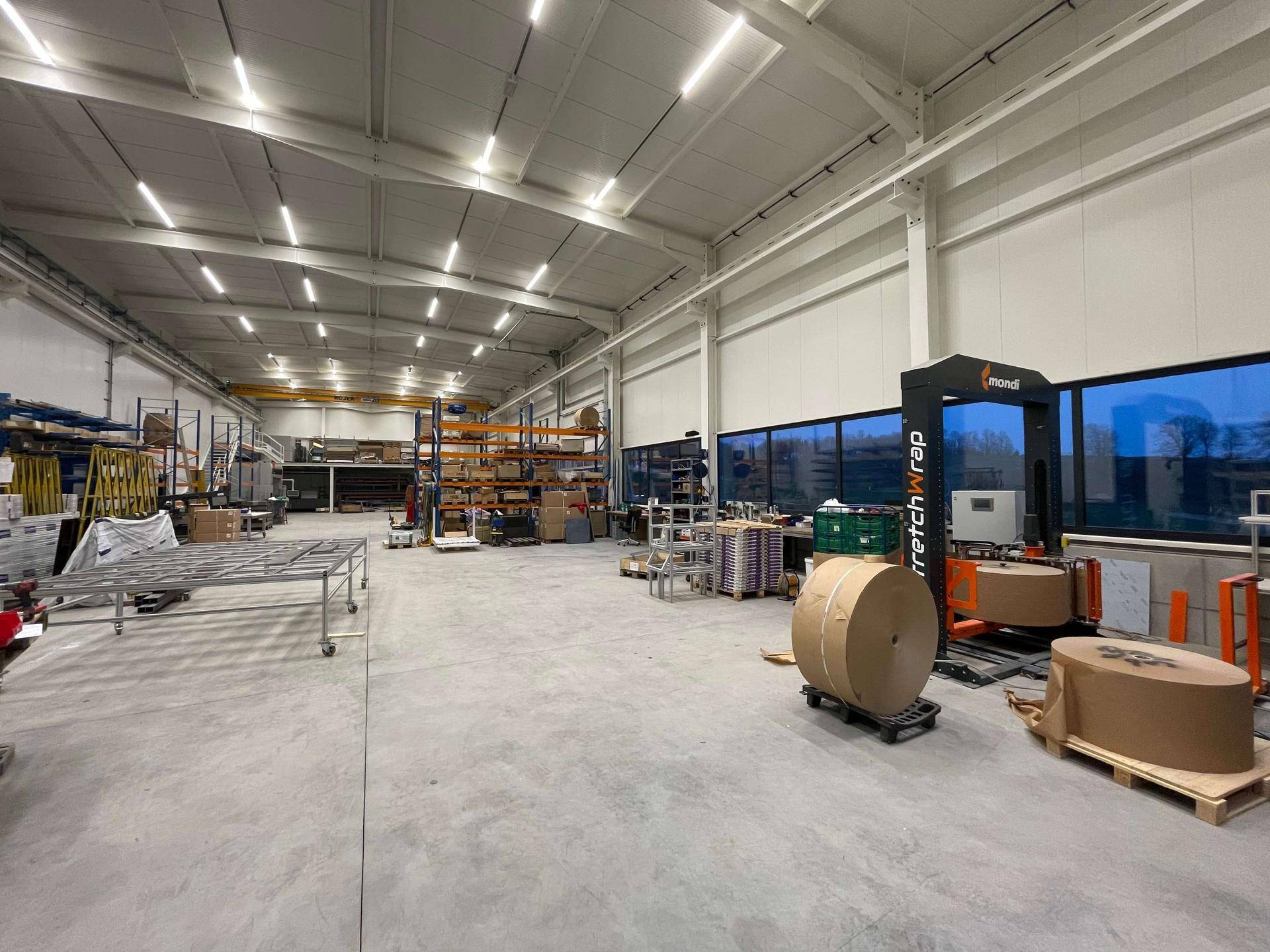 Geräumige Produktionshalle mit hohen Decken, großen Fenstern und industriellen Maschinen.