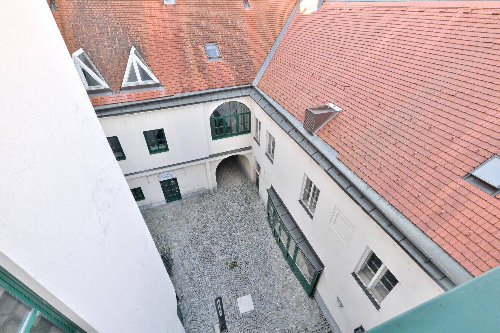 Vogelperspektive auf den Innenhof mit Kopfsteinpflaster und die roten Dächer der umliegenden historischen Gebäude.