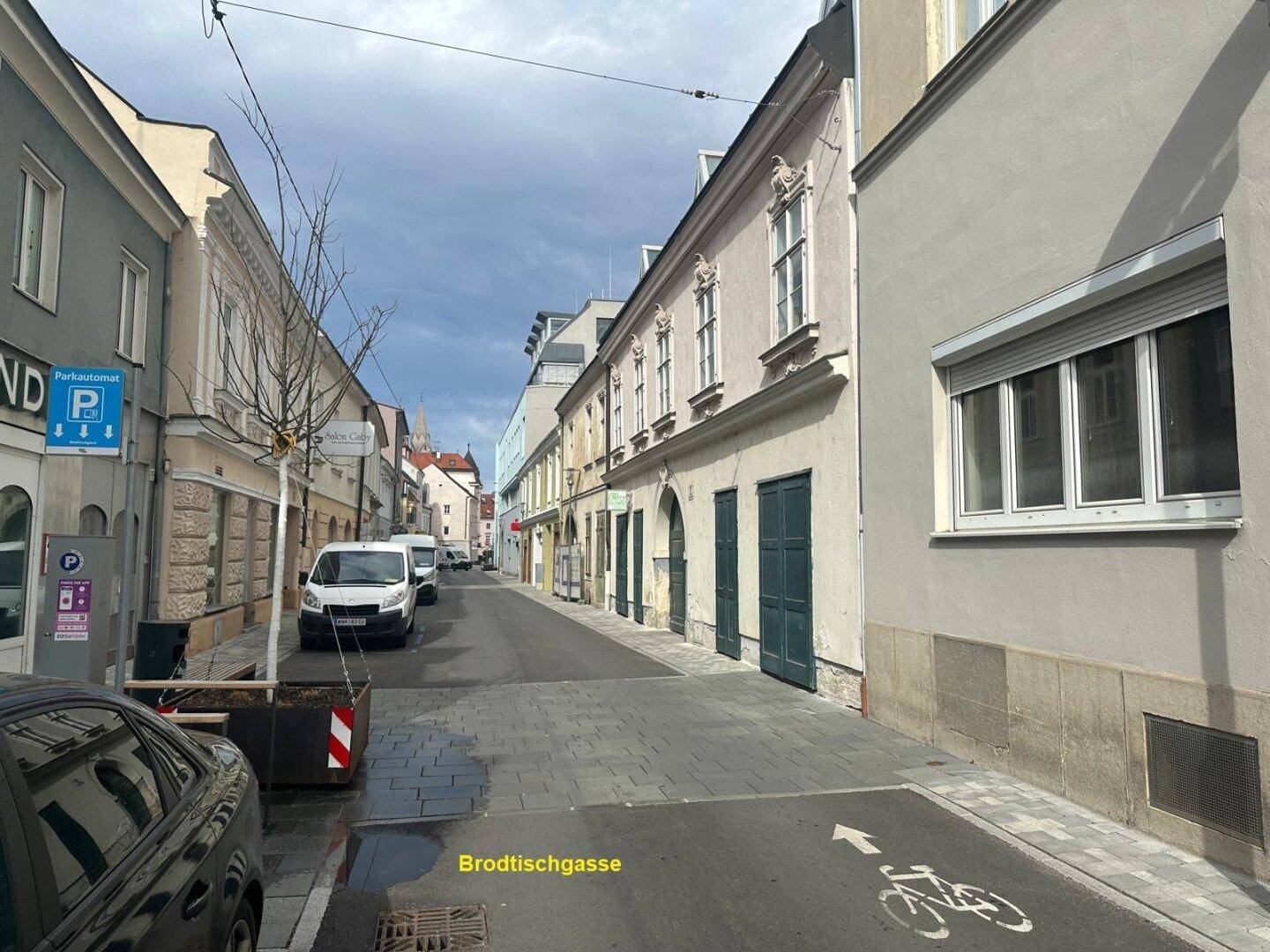 Ruhige Straße mit parkenden Autos und historischen Gebäuden, die eine charmante Stadtansicht bieten.