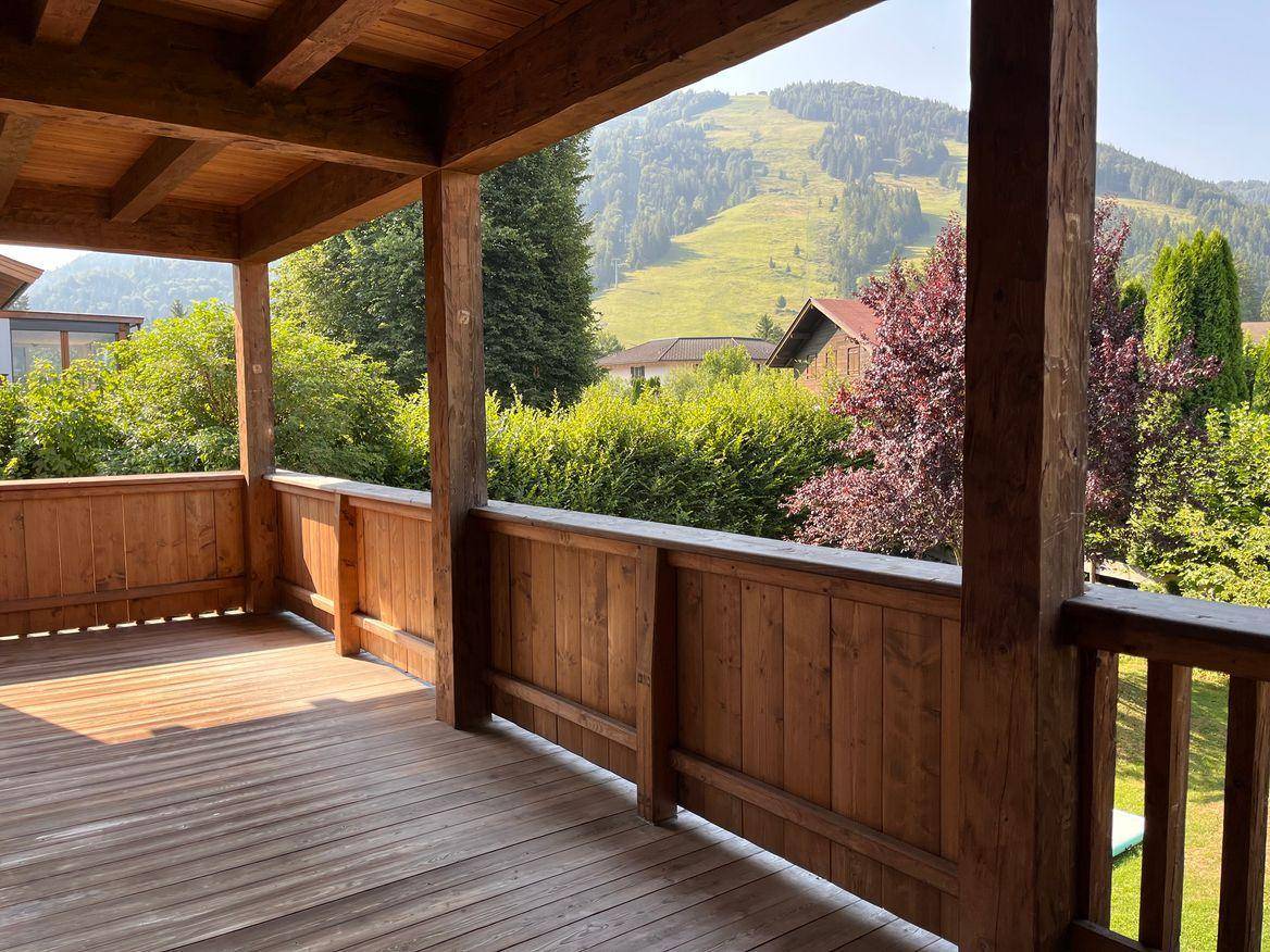 Sonniger Holzbalkon mit rustikalem Charme und weitem Blick auf die umliegende Berglandschaft.
