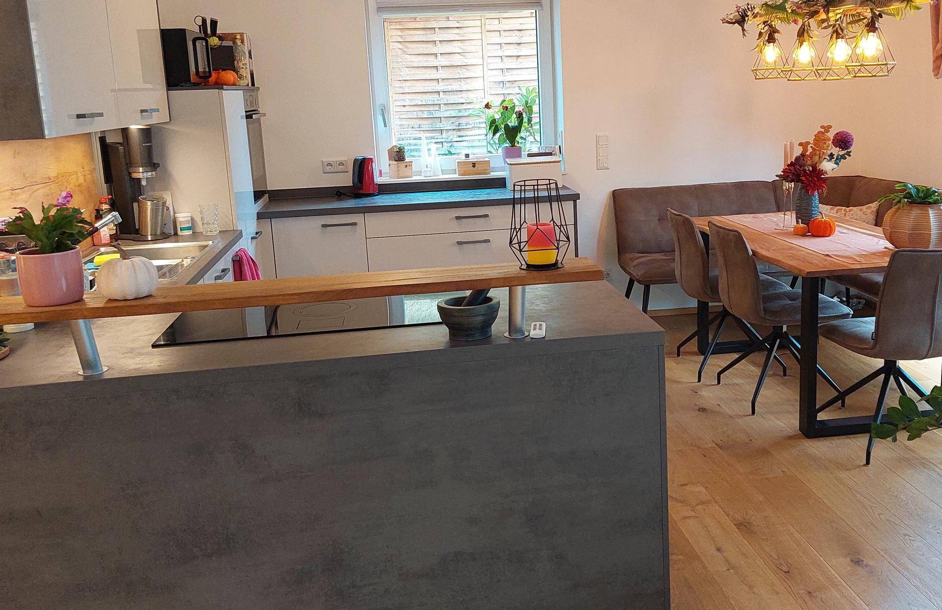 Moderne Küche mit Kochinsel und angrenzendem Essbereich, ausgestattet mit Holztisch und Sitzbank.