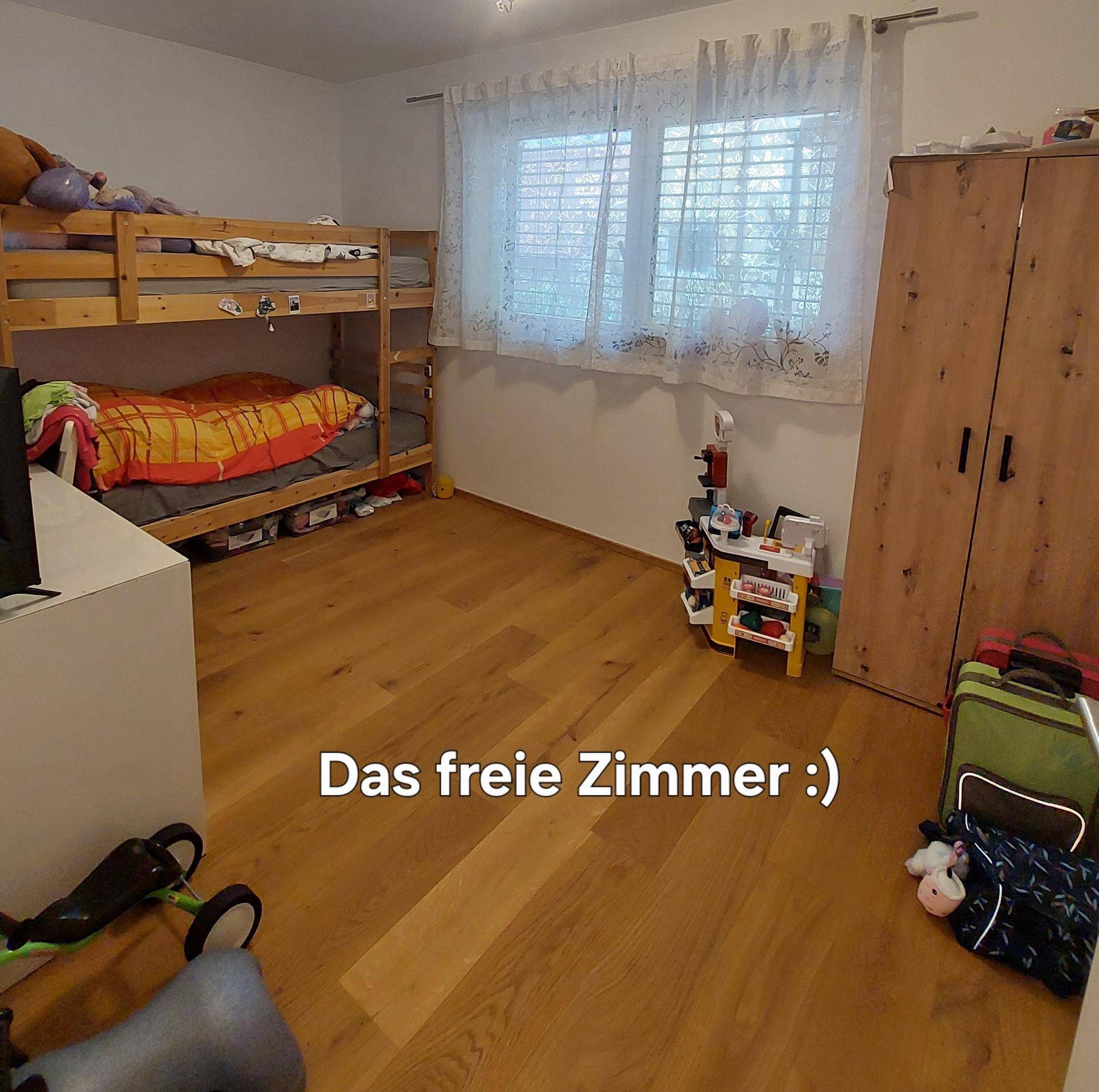 Kinderzimmer mit Etagenbett und Holzfußboden, hell durch das Fenster mit Jalousien.