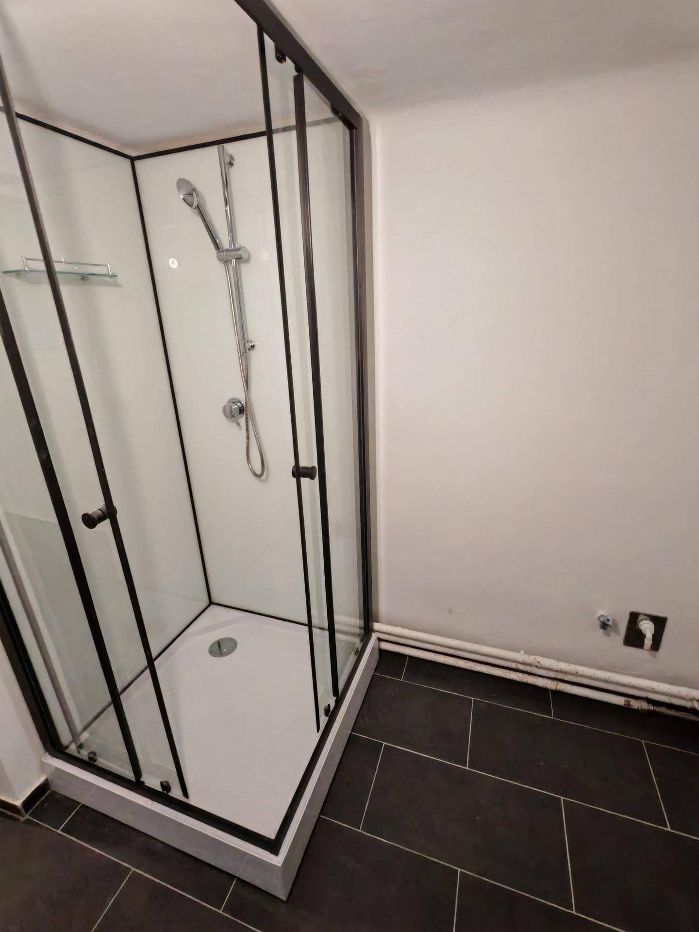 Moderne Duschkabine mit schwarzen Rahmen und klaren Glaswänden im Badezimmer.