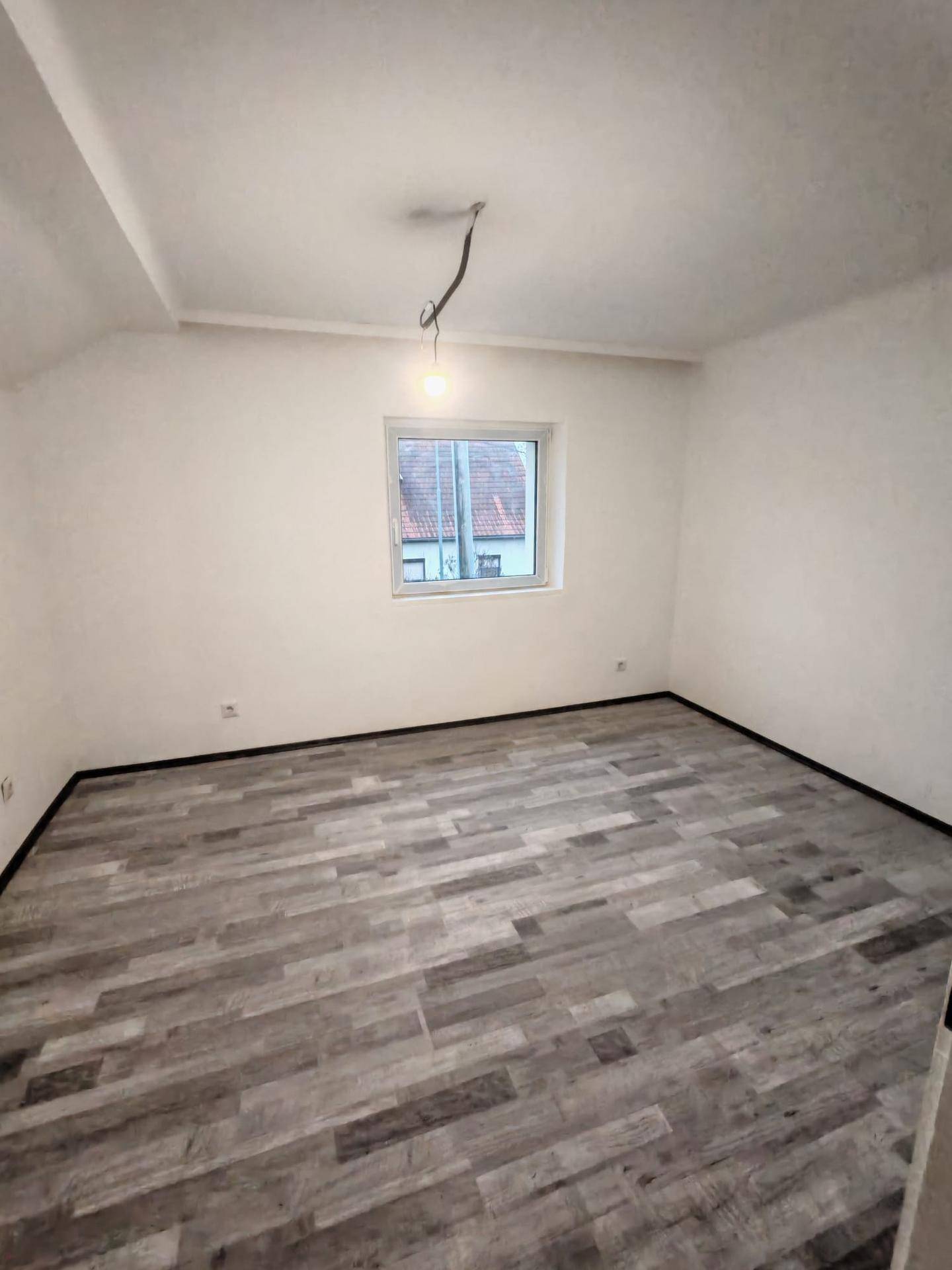 Helles Zimmer mit Laminatboden und Fenster, ideal als Schlaf- oder Arbeitszimmer.