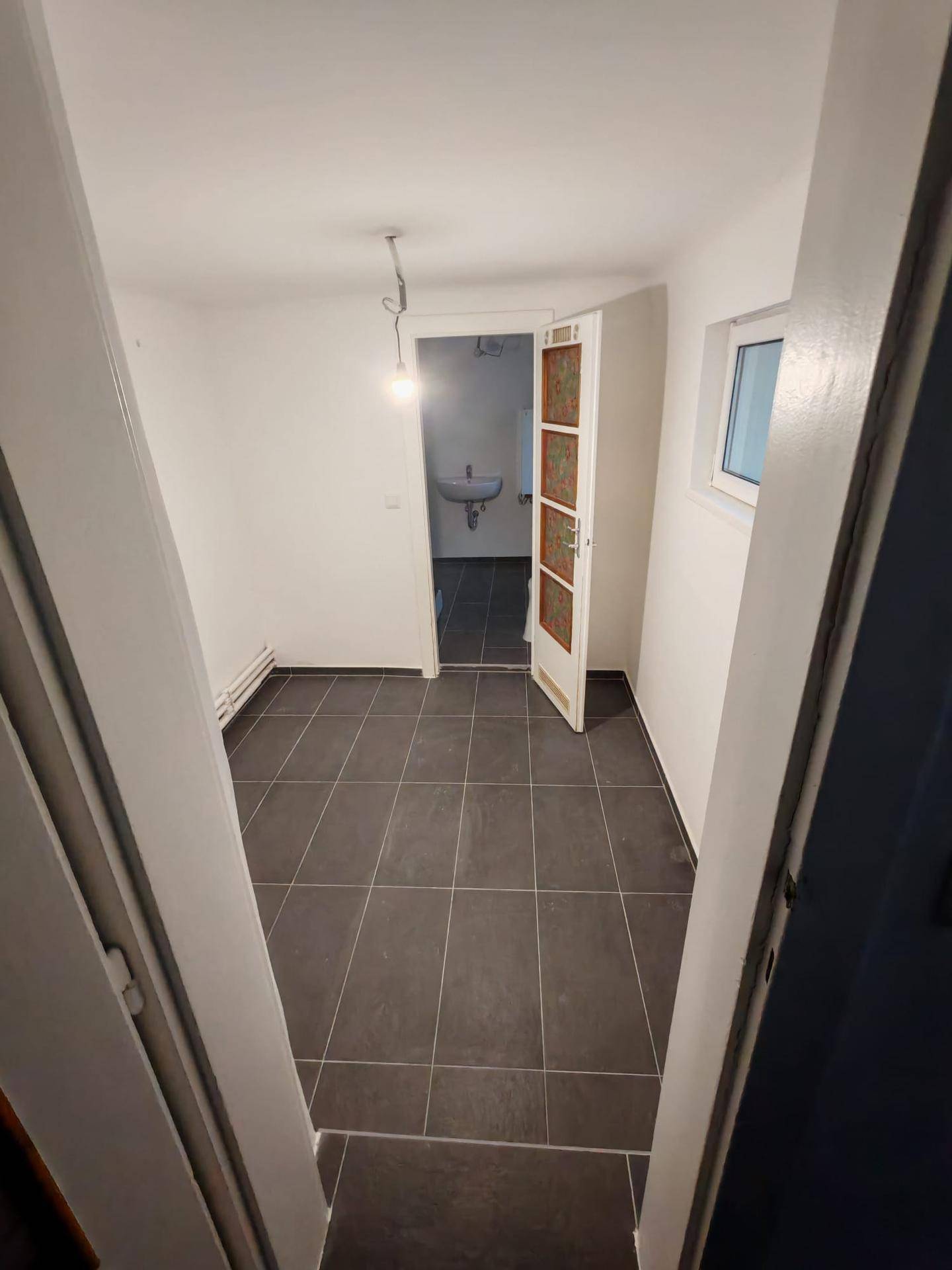 Kleiner Flur mit dunklem Fliesenboden, der zum Badezimmer führt.