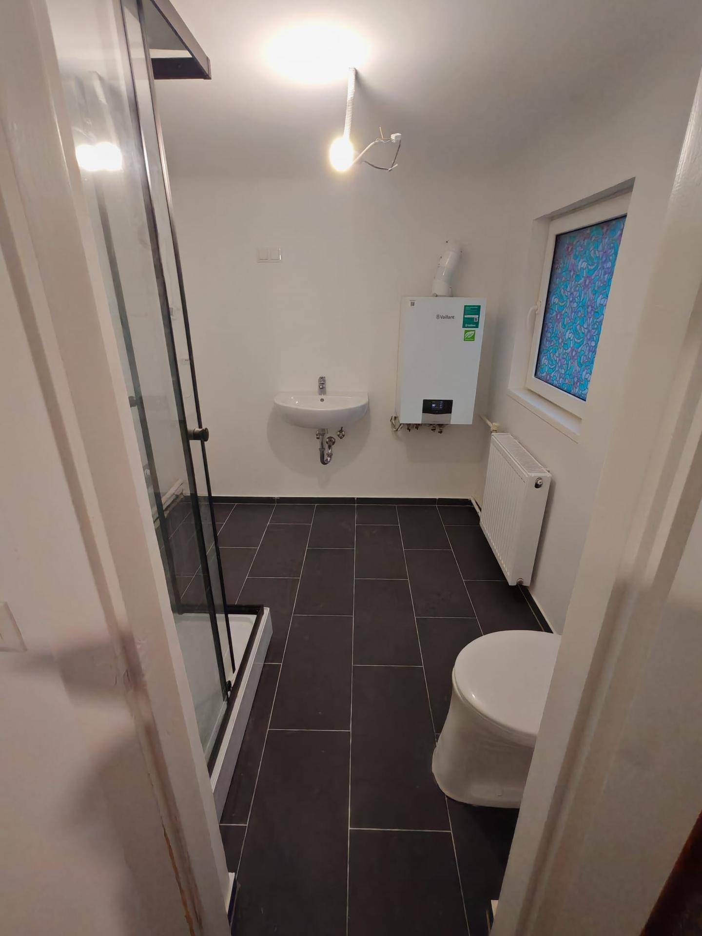 Modernes Badezimmer mit Duschkabine, WC, Waschbecken und einem Fenster.