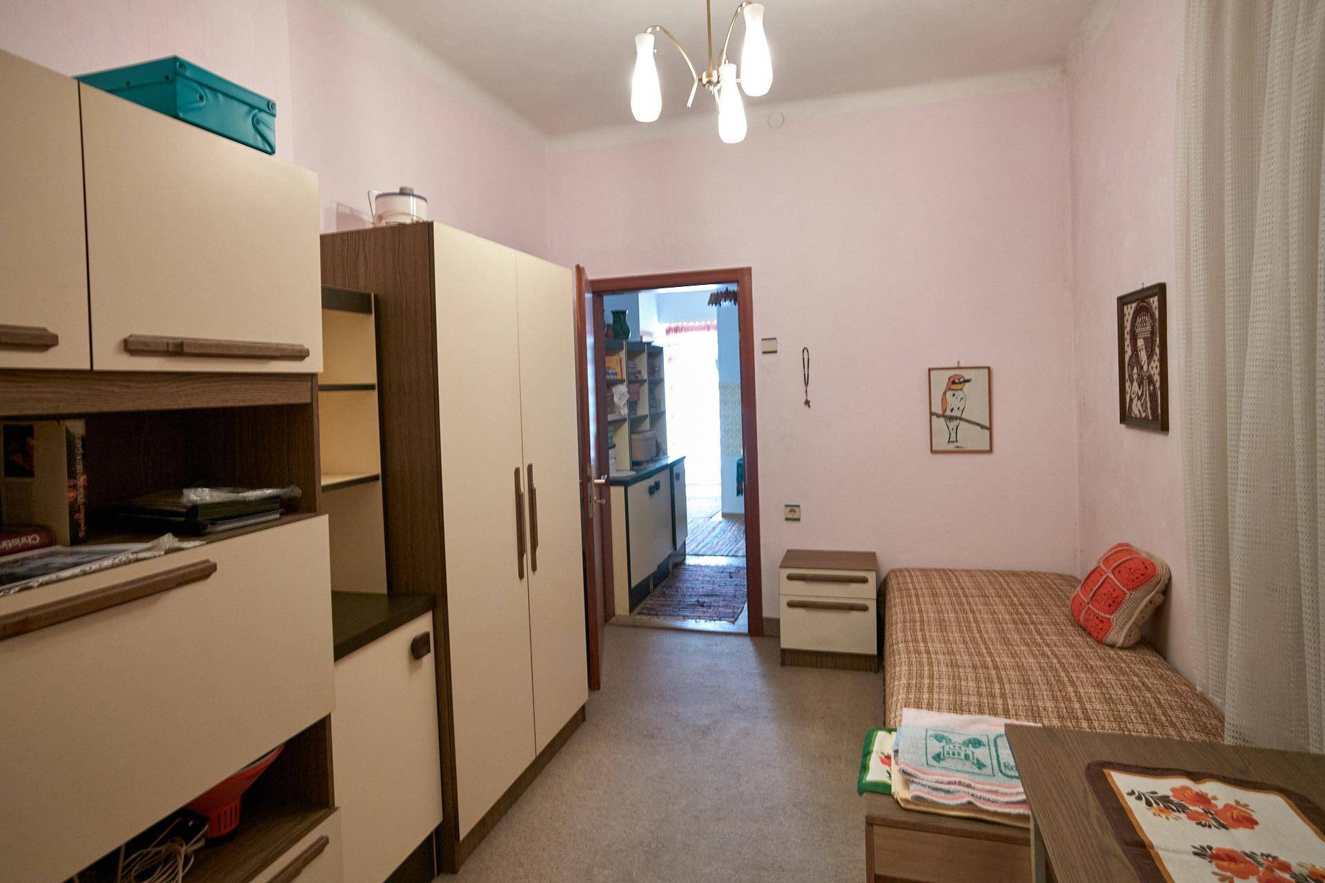 Kleines Schlafzimmer mit rosa Wänden, Einzelbett und praktischen Einbauschränken.