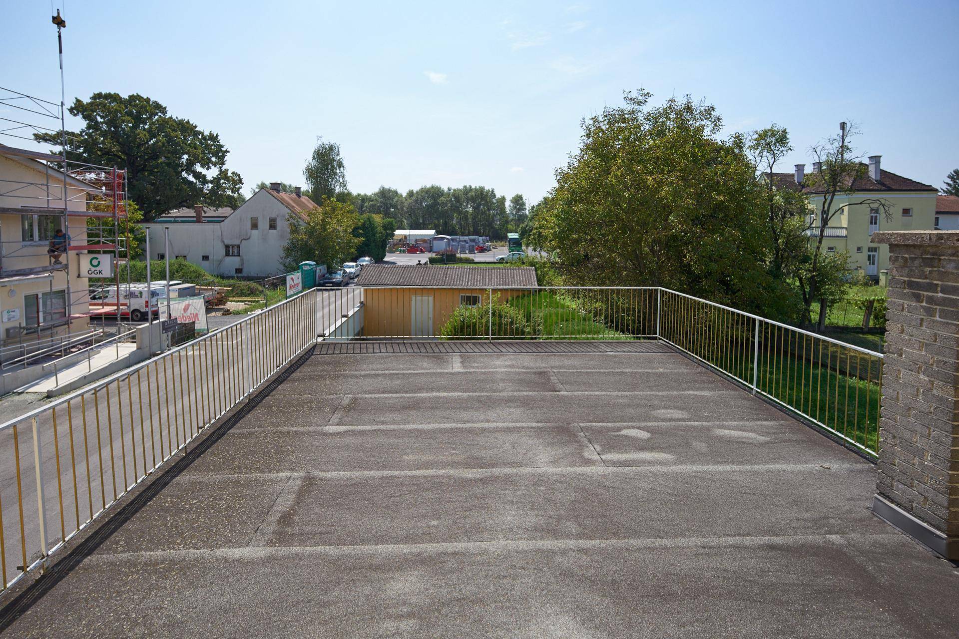 Geräumige Dachterrasse mit Metallgeländer und Blick auf die umliegende Bebauung.