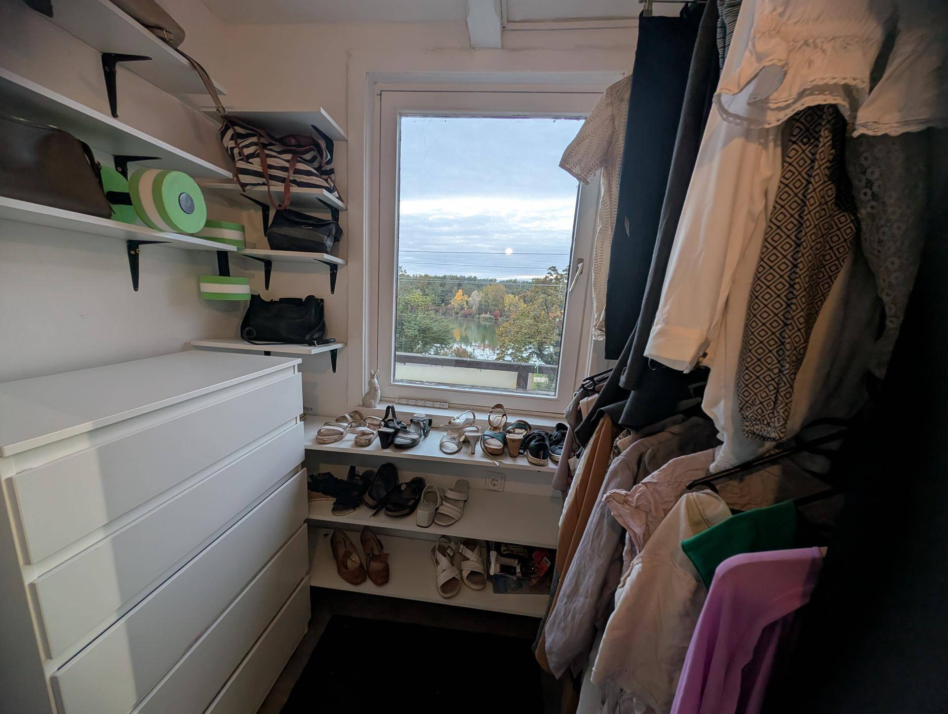 Begehbarer Kleiderschrank mit Regalen, Kommode und Fenster mit weitem Ausblick.