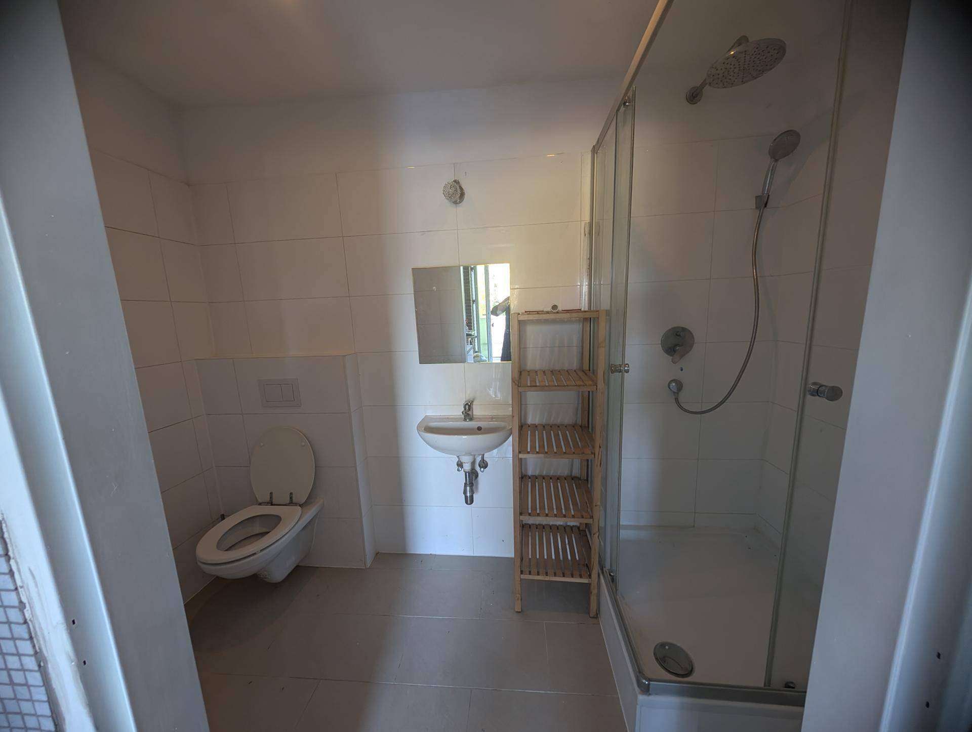 Modernes Badezimmer mit Dusche, Hänge-WC, Einzelwaschbecken und minimalistischem Design.