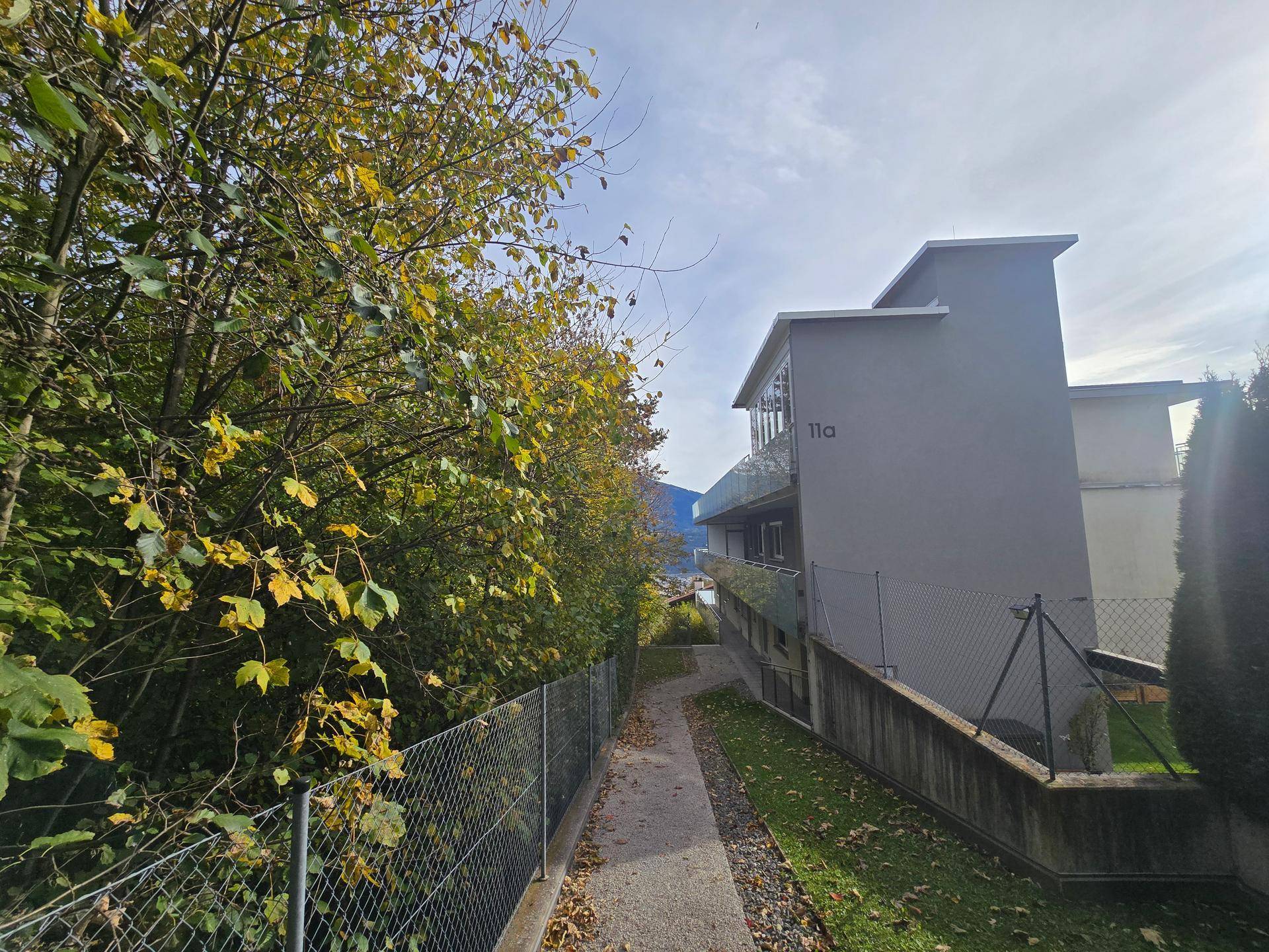 Ansicht des modernen Gebäudes mit einem schmalen Zugangsweg und herbstlichem Laub.