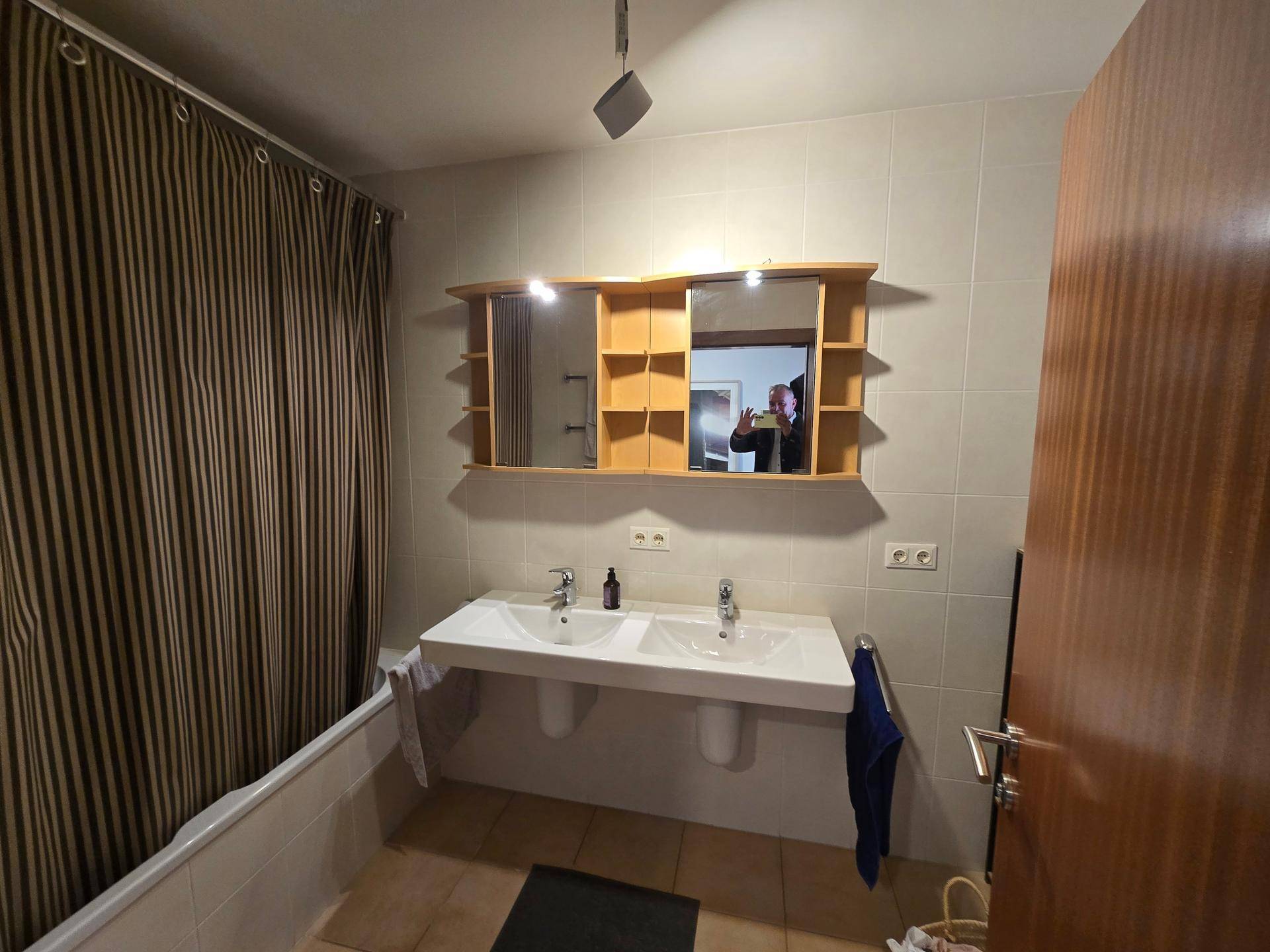 Badezimmer mit Doppelwaschbecken, Badewanne und großem Spiegelschrank.