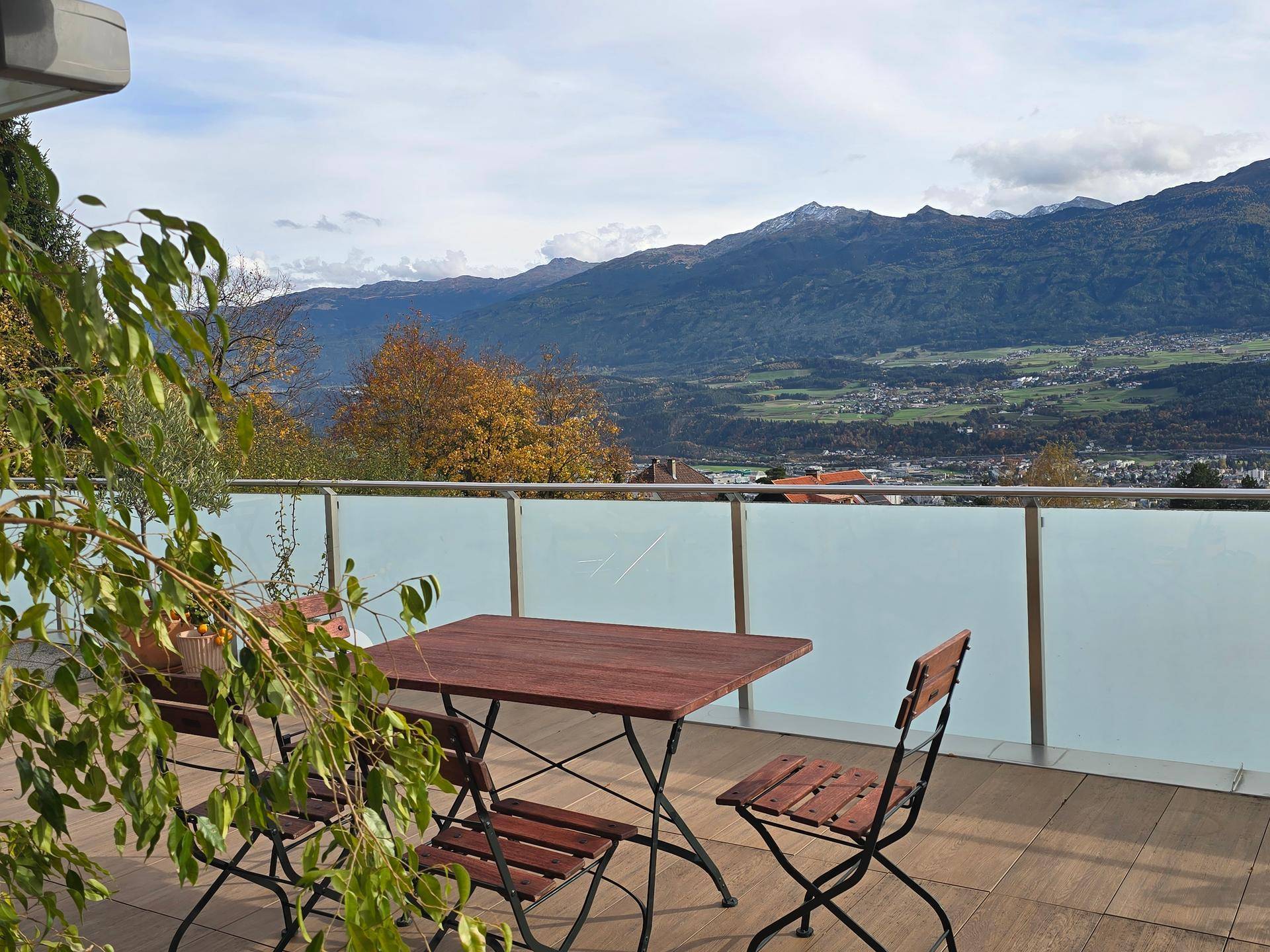 Möblierte Terrasse mit Holzboden und Panoramablick auf die Berge und die Landschaft.