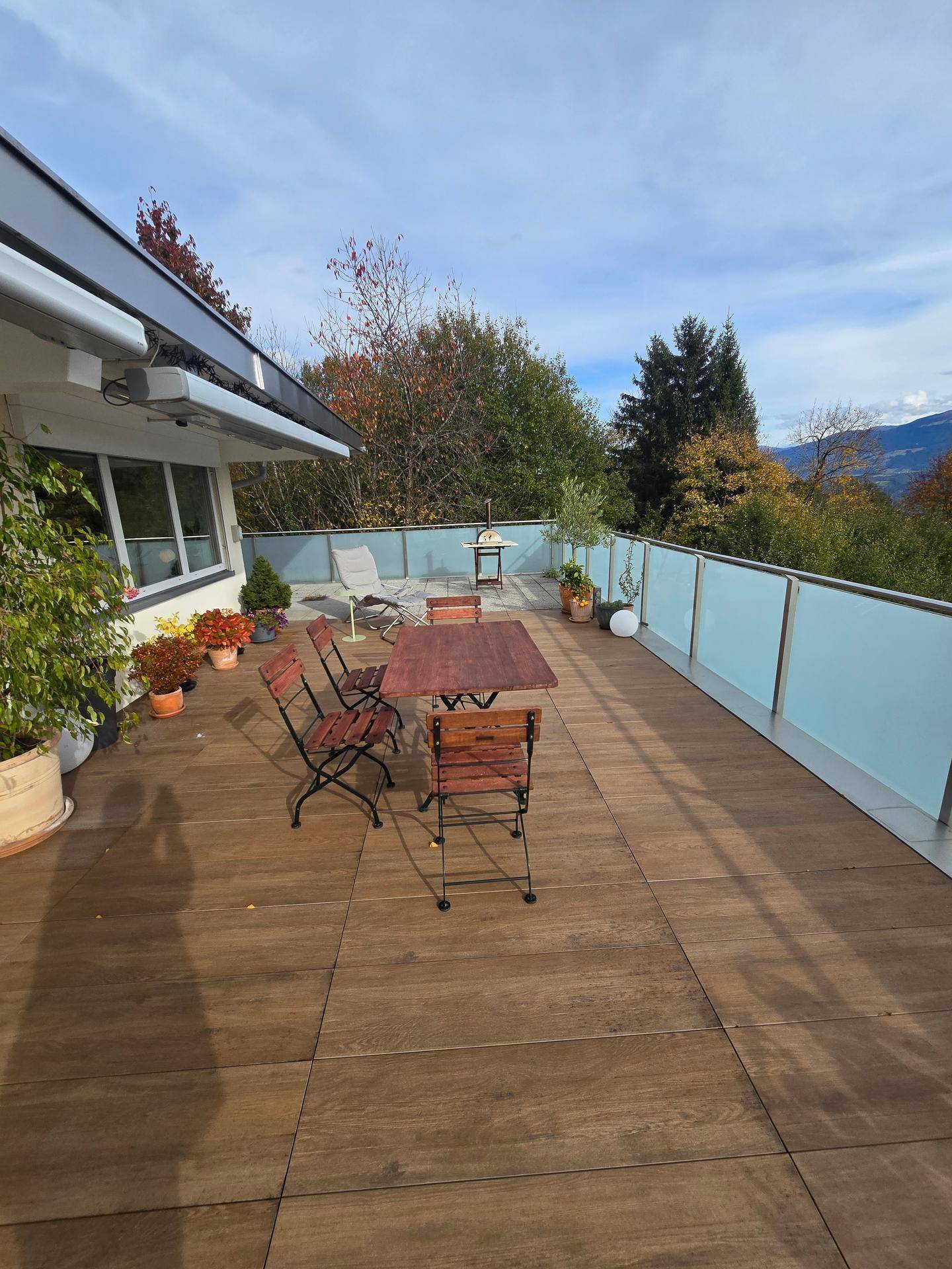 Sonniger Terrassenbereich mit Holzboden und Gartenmöbeln, ideal zum Entspannen im Freien.
