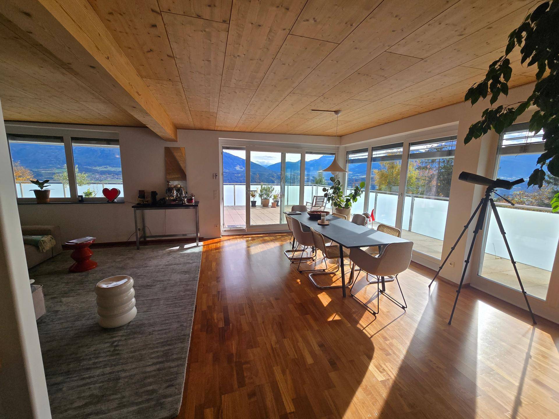 Lichtdurchfluteter Wohn- und Essbereich mit Holzboden, Bergblick und Zugang zur Terrasse.