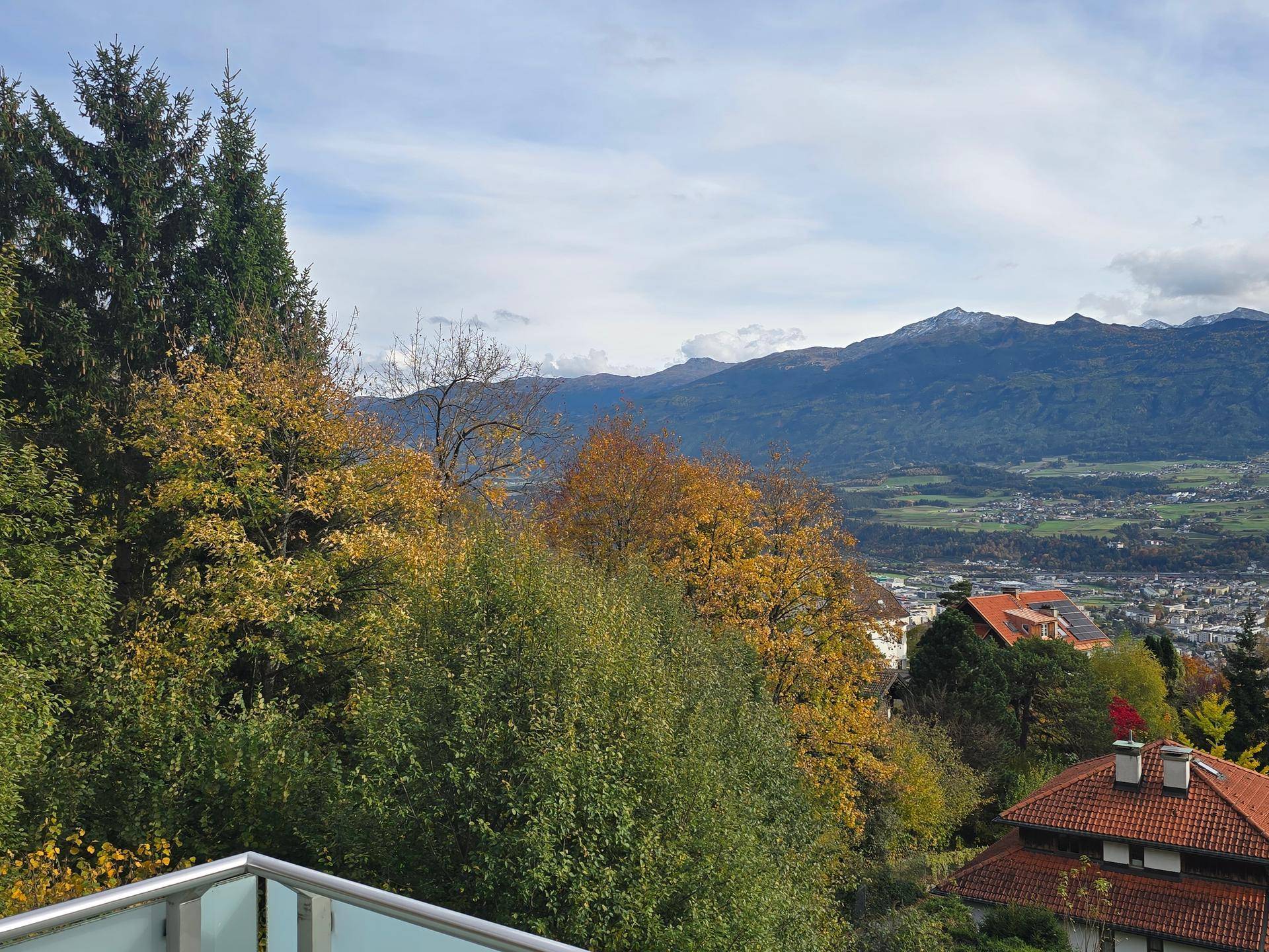 Terrasse mit Glasgeländer und weitem Blick auf die Stadt und die umliegenden Berge.