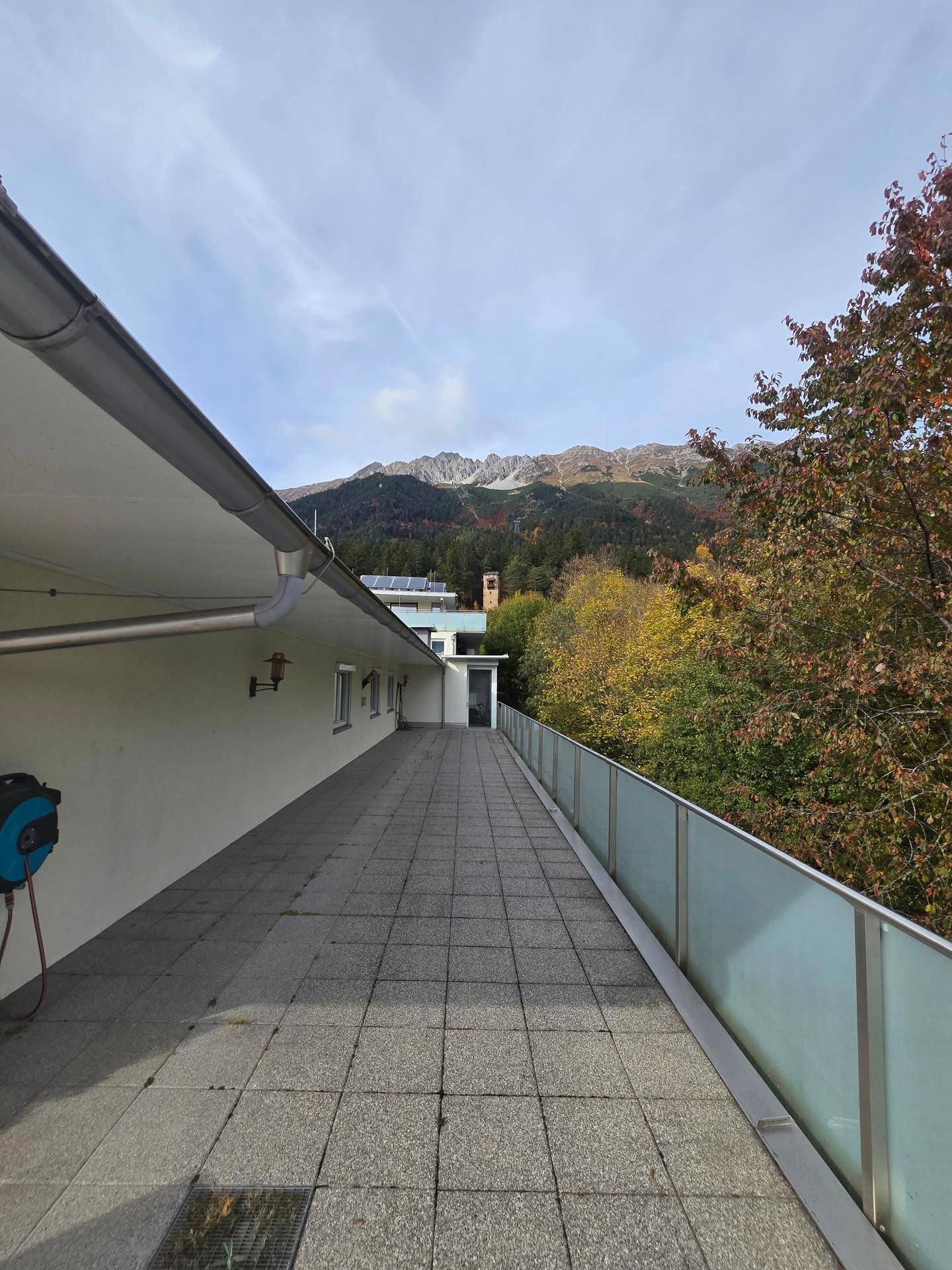 Weitläufiger Terrassenbereich mit Fliesenboden und beeindruckendem Blick auf die Berge.