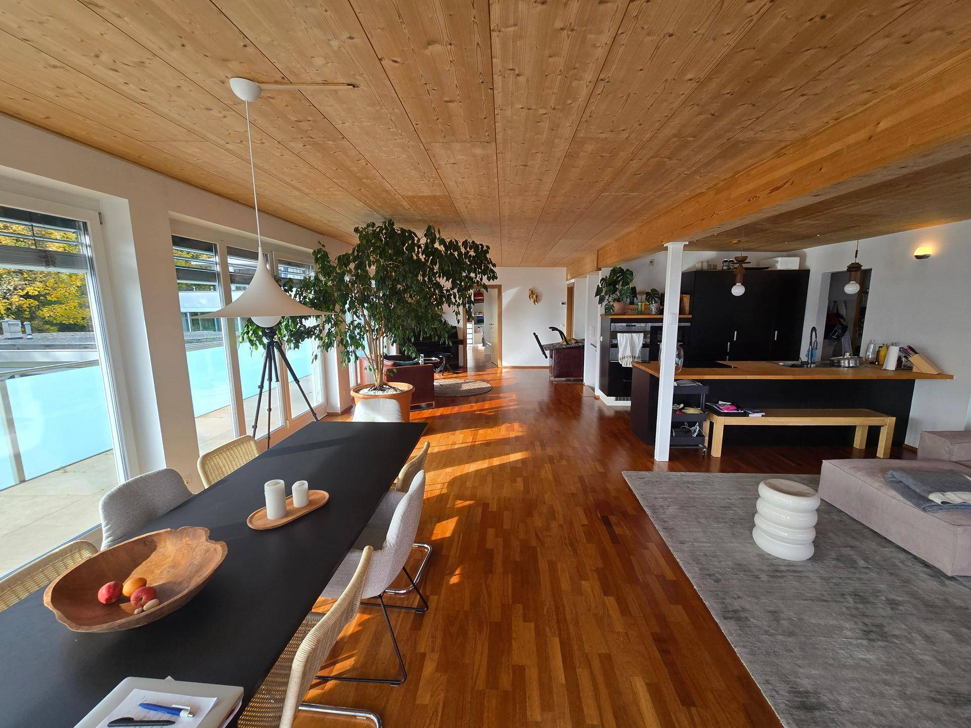 Offener Wohn- und Essbereich mit Holzboden, integrierter Küche und Zugang zur Terrasse.