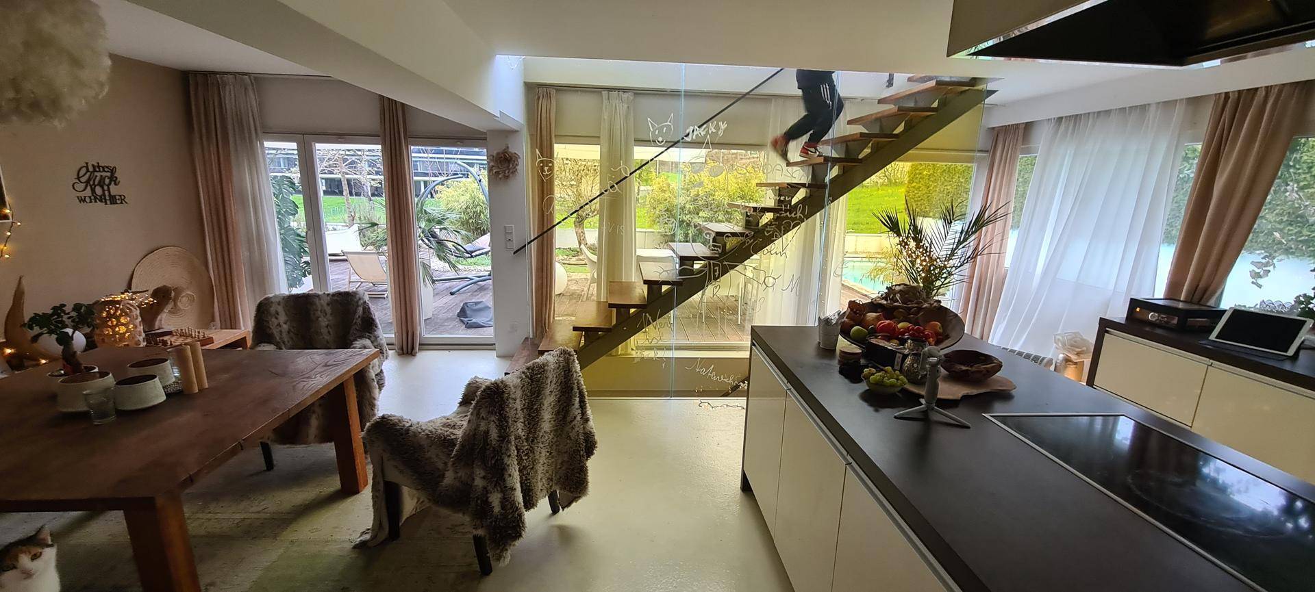 Moderner offener Wohn-Essbereich mit Kücheninsel, Holztisch und Blick auf den Garten.