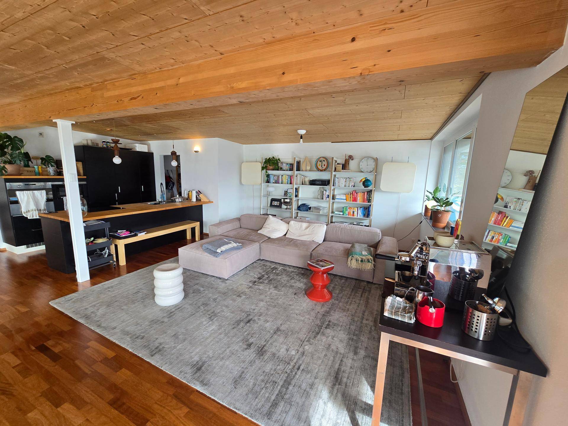 Geräumiger Wohnbereich mit Holzboden, offener Küche und großem Sofa.