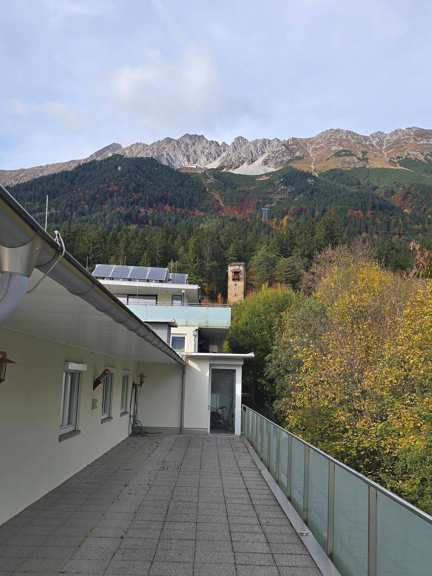 Langer Terrassenbereich mit Fliesenboden und weitem Blick auf die Berge und die Natur.