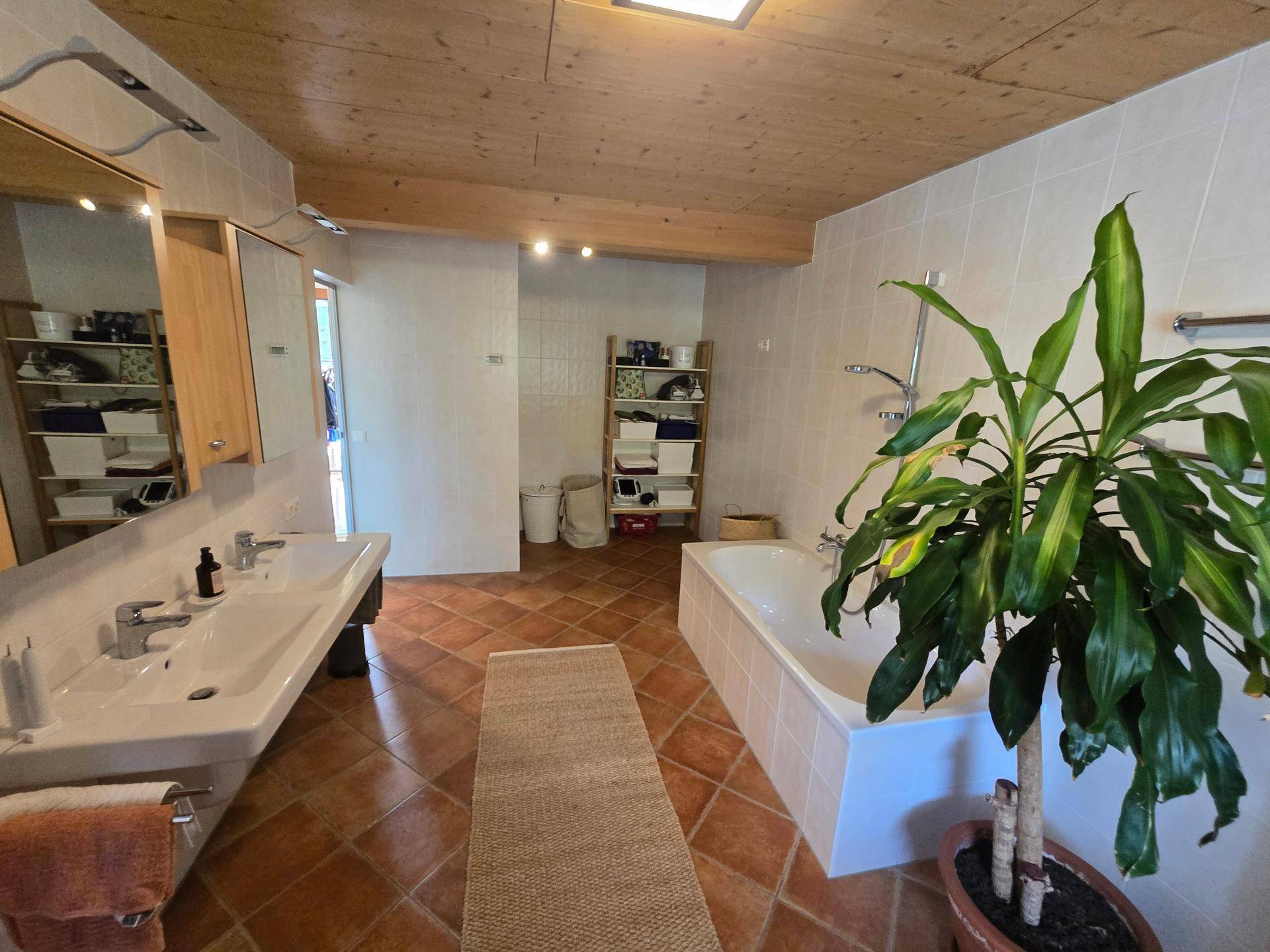 Geräumiges Badezimmer mit Badewanne, Doppelwaschbecken und Terrakottafliesen.