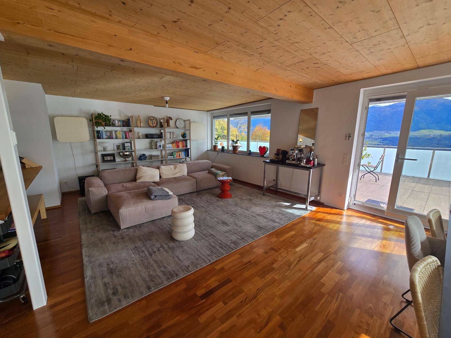 Geräumiger Wohnbereich mit Holzboden, offener Küche und großem Sofa.